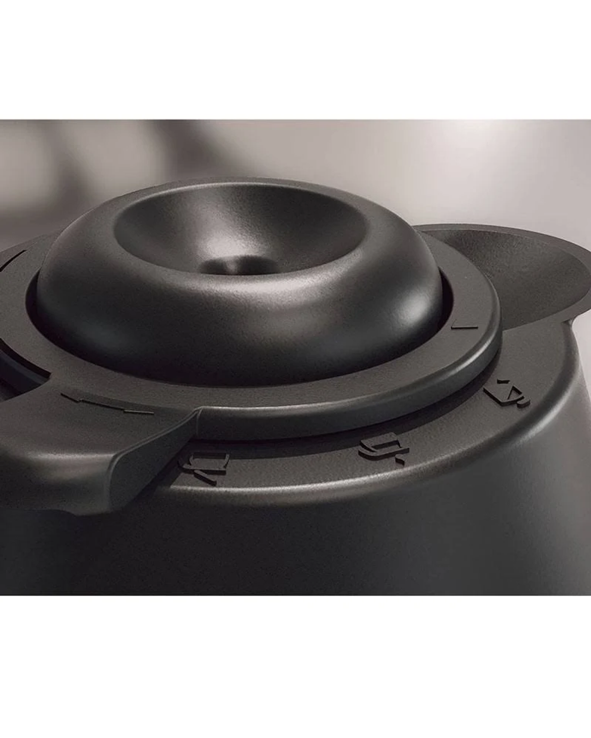 Zbliżenie czarnego pokrętła urządzenia ze strzałkami i symbolami. Tło jest rozmyte.