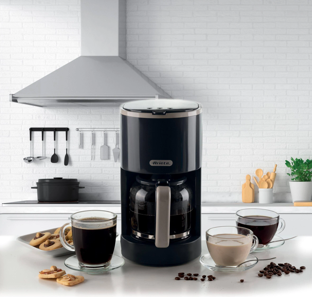 Czarny ekspres do kawy z filiżankami kawy i ciasteczkami na tle białej ceglanej ściany.