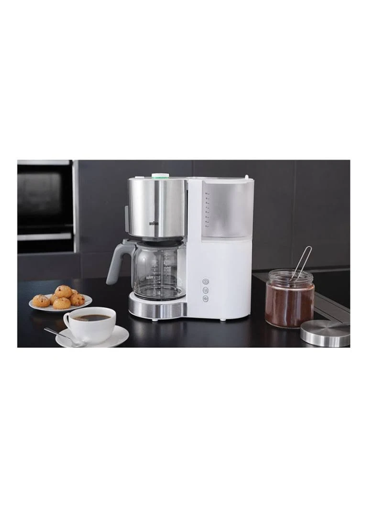 Kaffeemaschine mit Glaskaraffe, weißem Gehäuse und einer Tasse Kaffee auf einem Tisch.