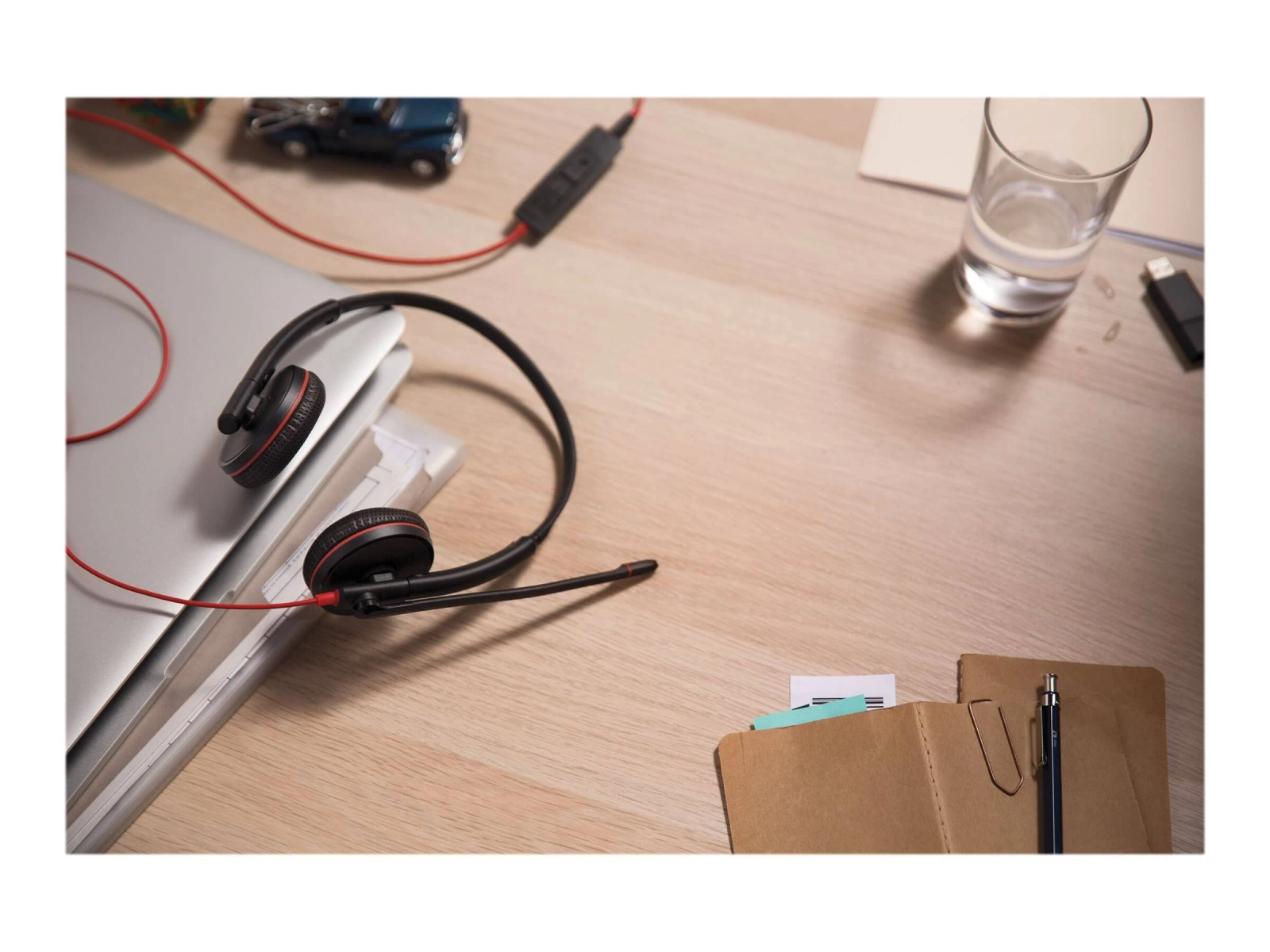 Auriculares, una laptop y otros objetos sobre un escritorio de madera.
