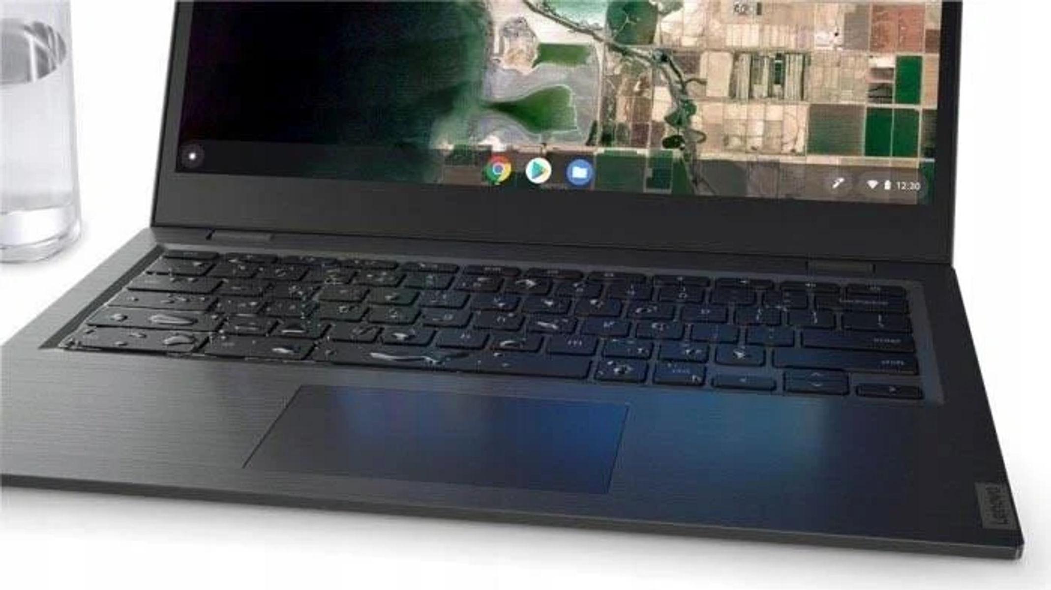Laptop con schermo che mostra una mappa aerea della città e una tastiera. C'è un bicchiere d'acqua.