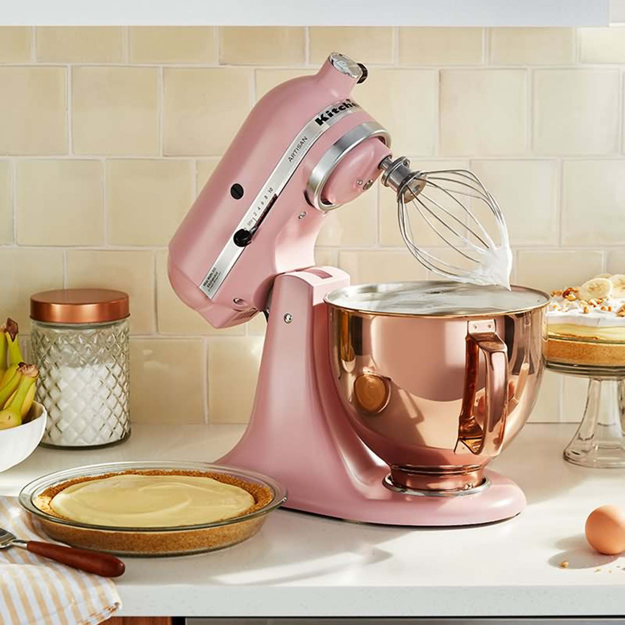 Ein pinkfarbener KitchenAid-Küchenmixer, der in einer Schüssel rührt, mit Kuchen und Zutaten.