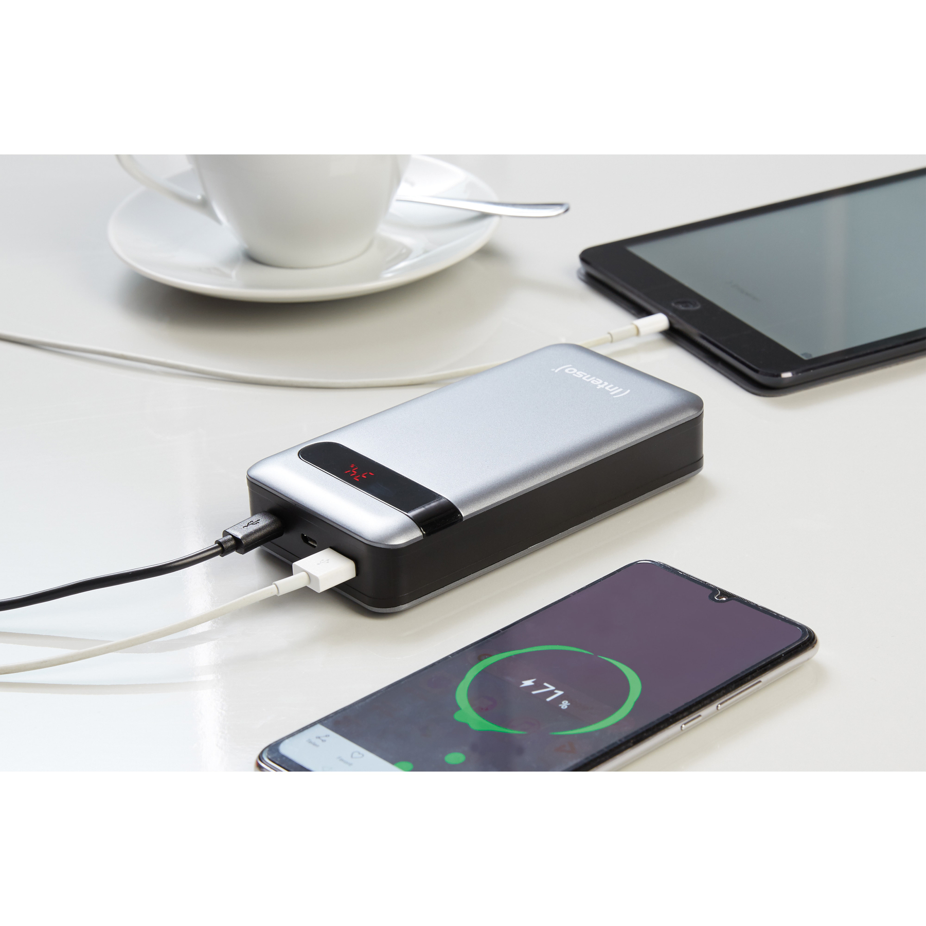 Een zilveren powerbank laadt een tablet en een telefoon op. De telefoon toont 71% opgeladen.
