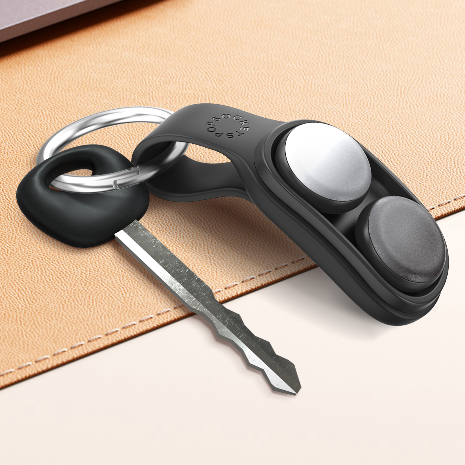 Portachiavi nero con chiave ed etichetta PopSockets su superficie beige.