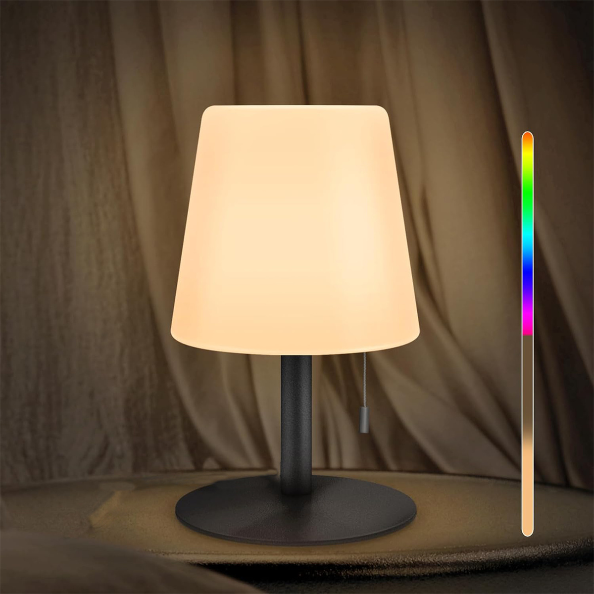 Tischlampe mit weißem Schirm, schwarzem Sockel und Farbspektrum-Indikator vor drapiertem Hintergrund.