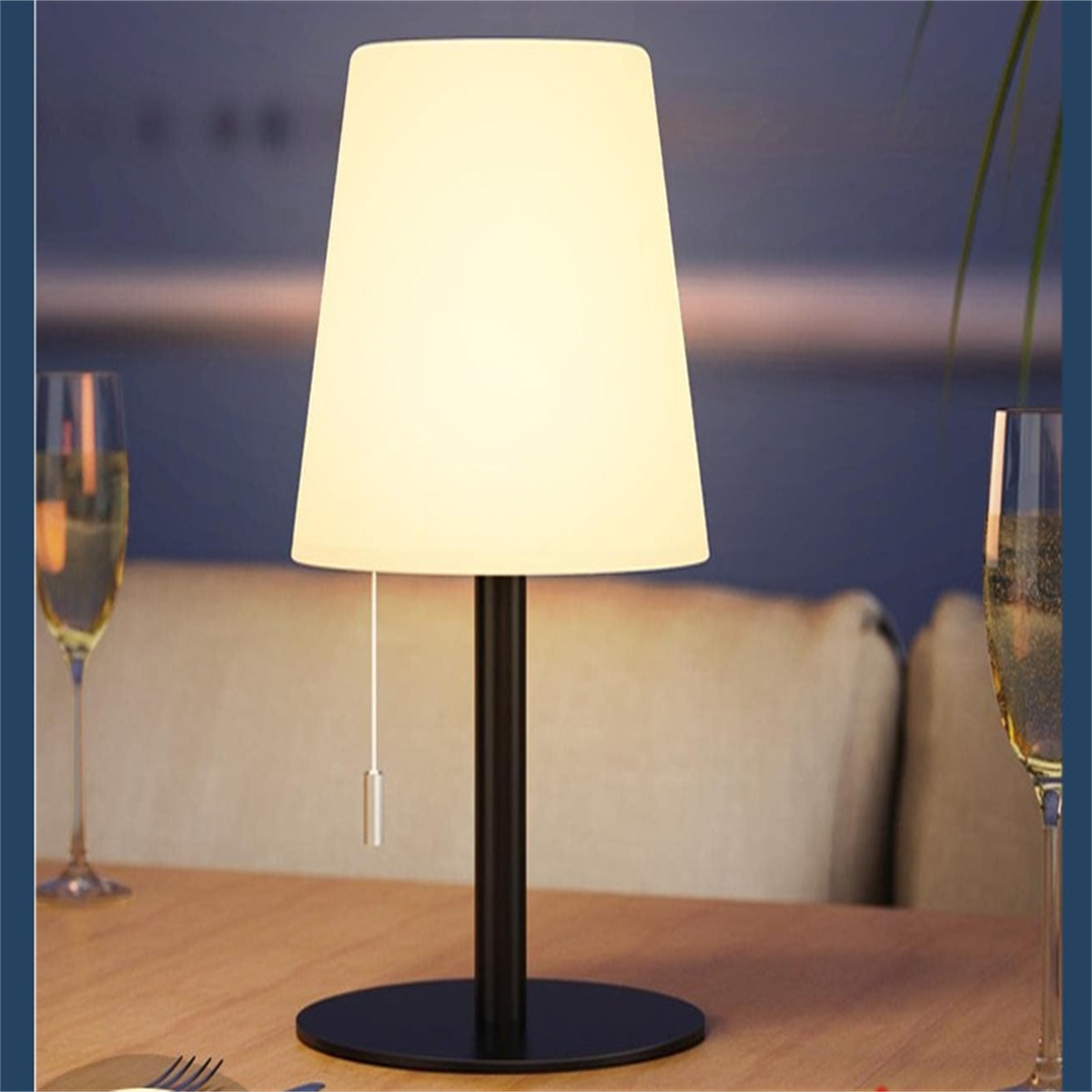 Tischlampe mit weißem Schirm auf Holztisch.