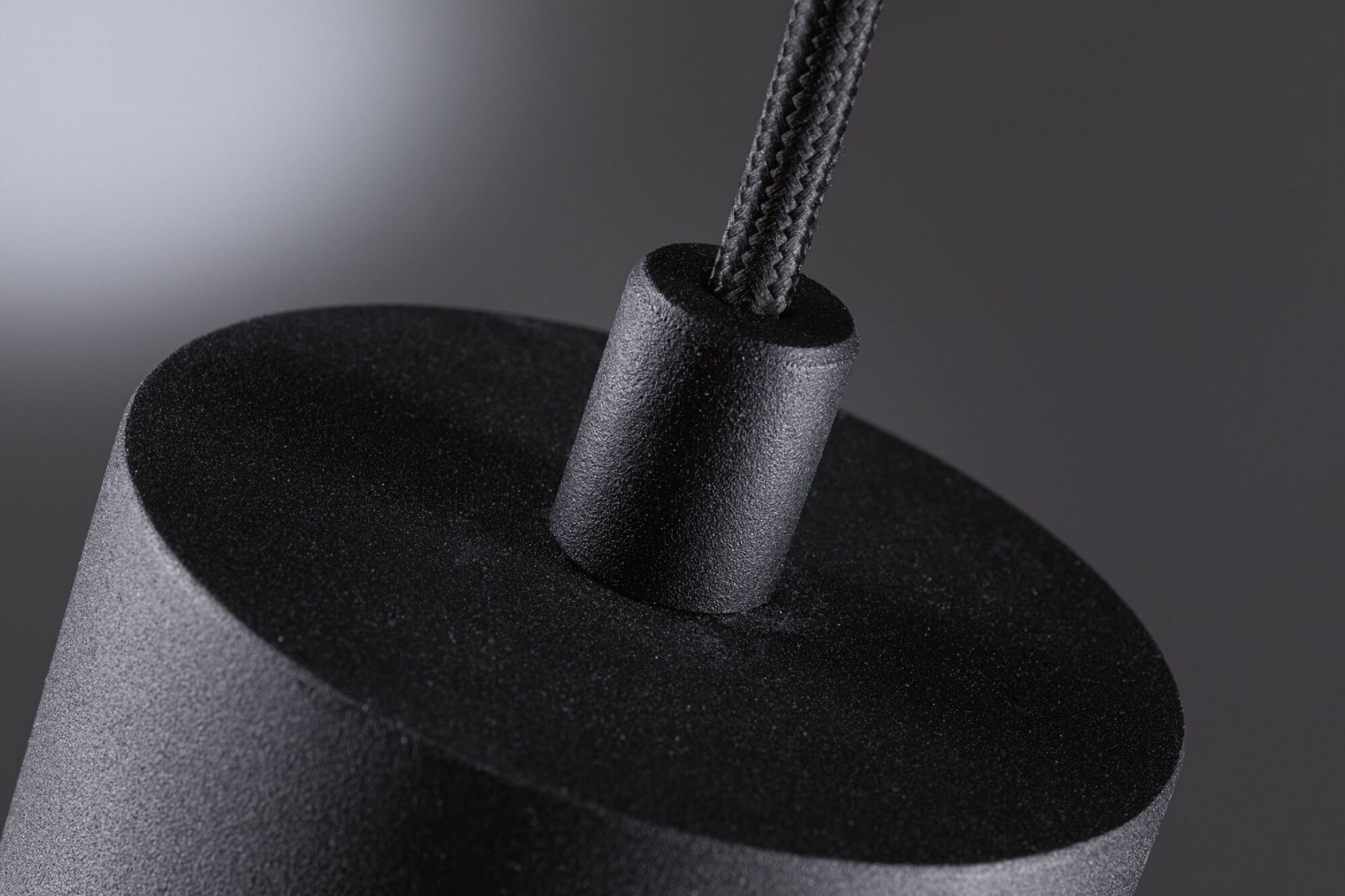 Zbliżenie czarnego cylindrycznego obiektu z czarnym przewodem podłączonym u góry.