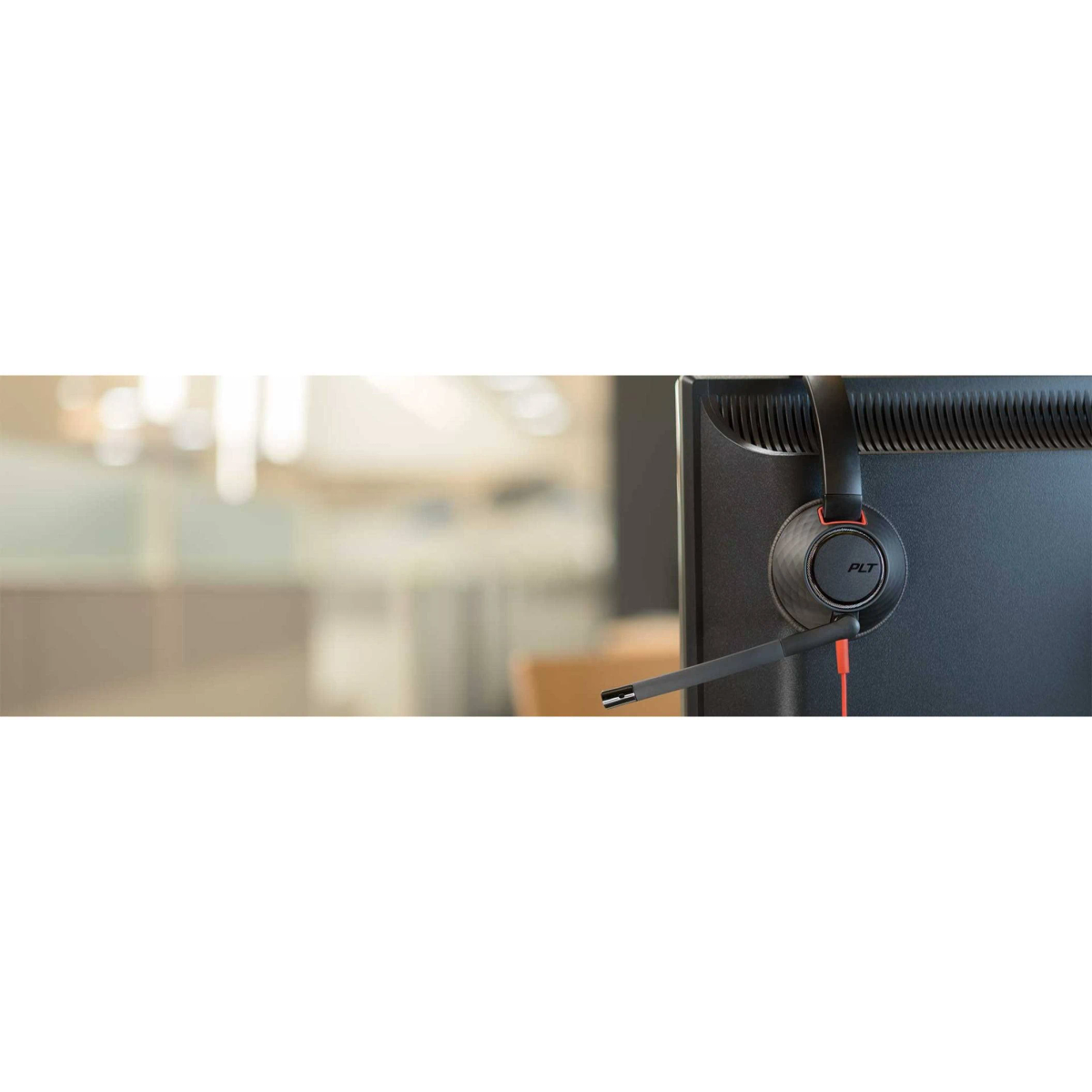 Auriculares en un monitor, diseño negro y rojo. Conectados al ordenador por cable.