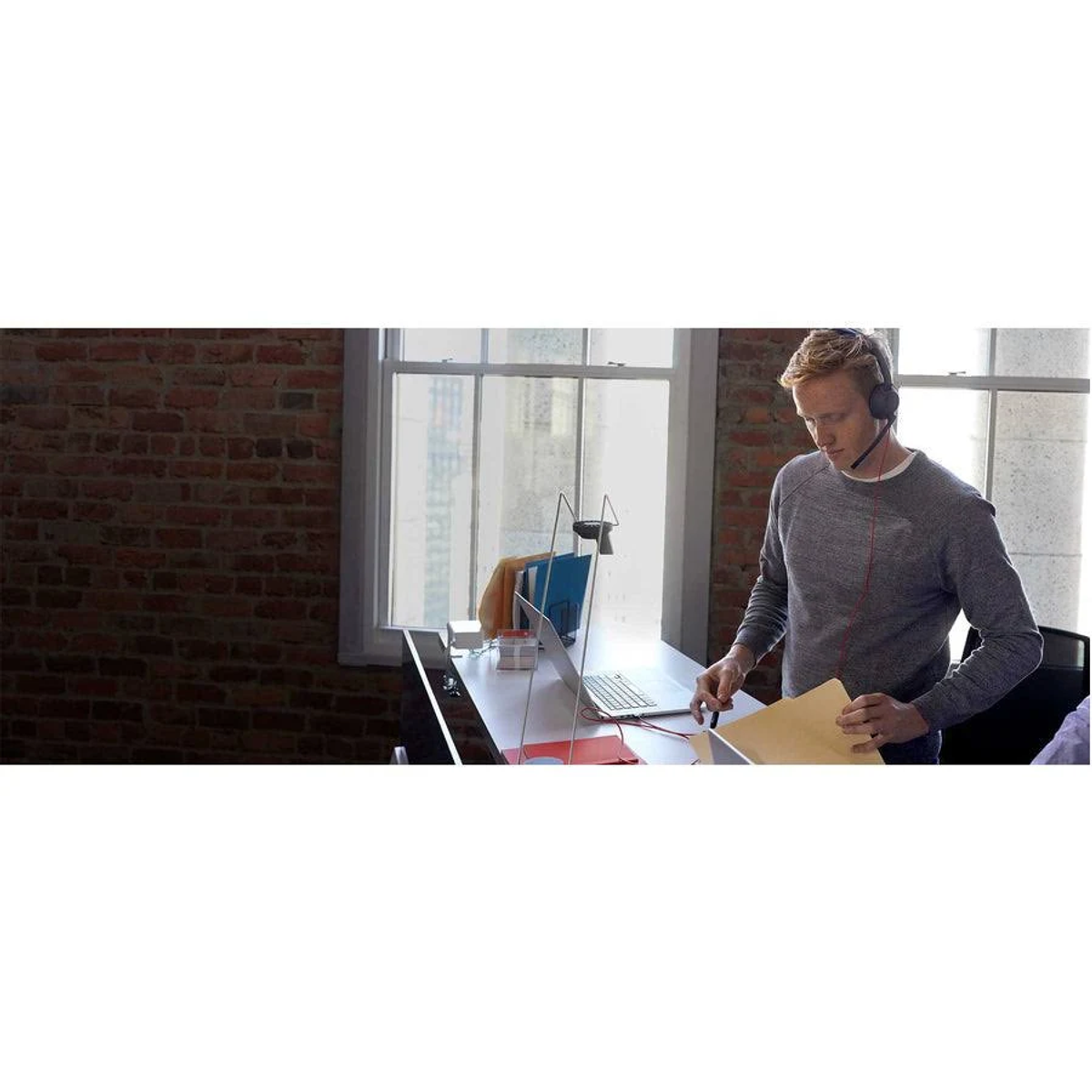 Un hombre con auriculares está en un escritorio. Sostiene un papel.