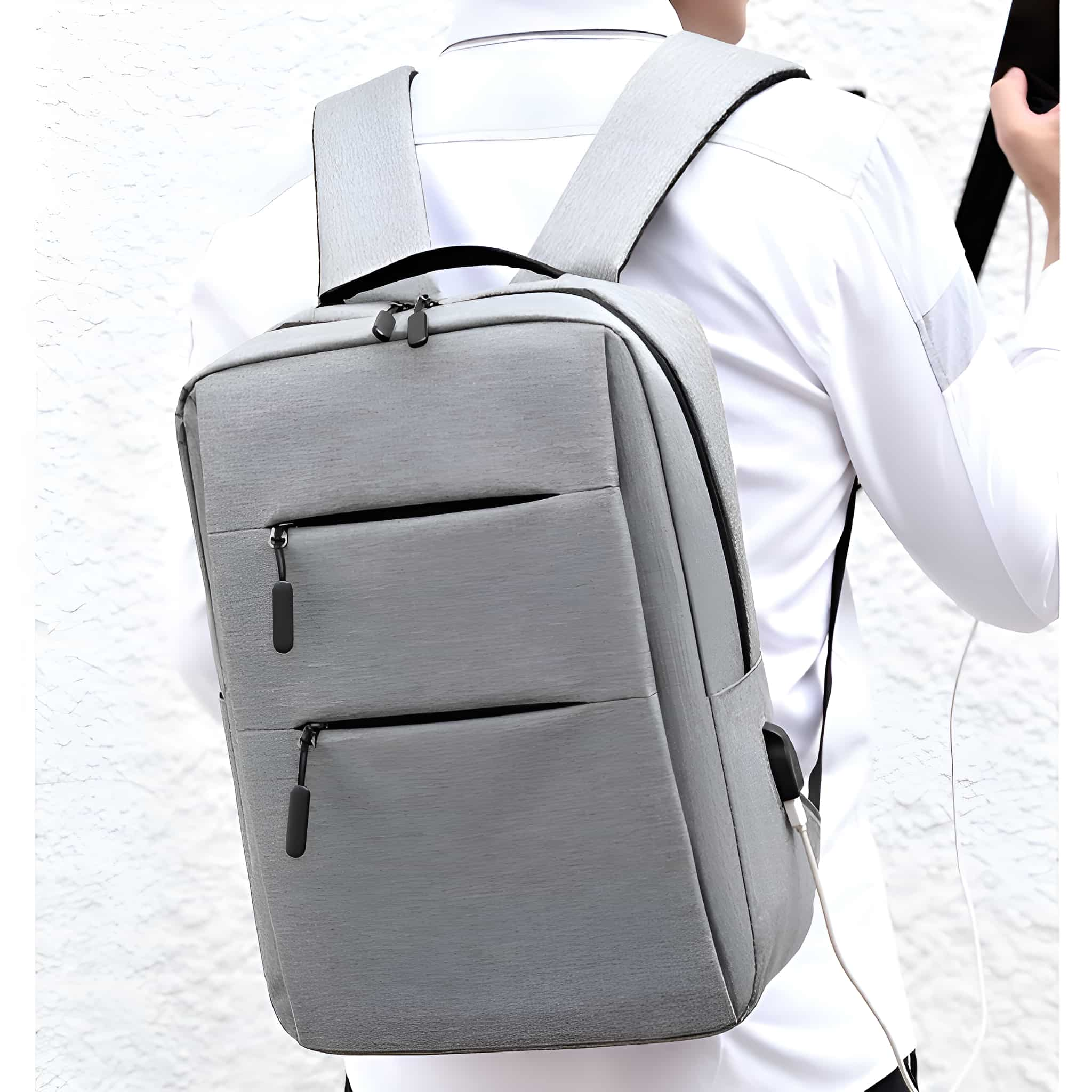 Mann mit grauem Rucksack auf weißem Hintergrund. Der Rucksack hat zwei Vordertaschen und einen USB-Anschluss.