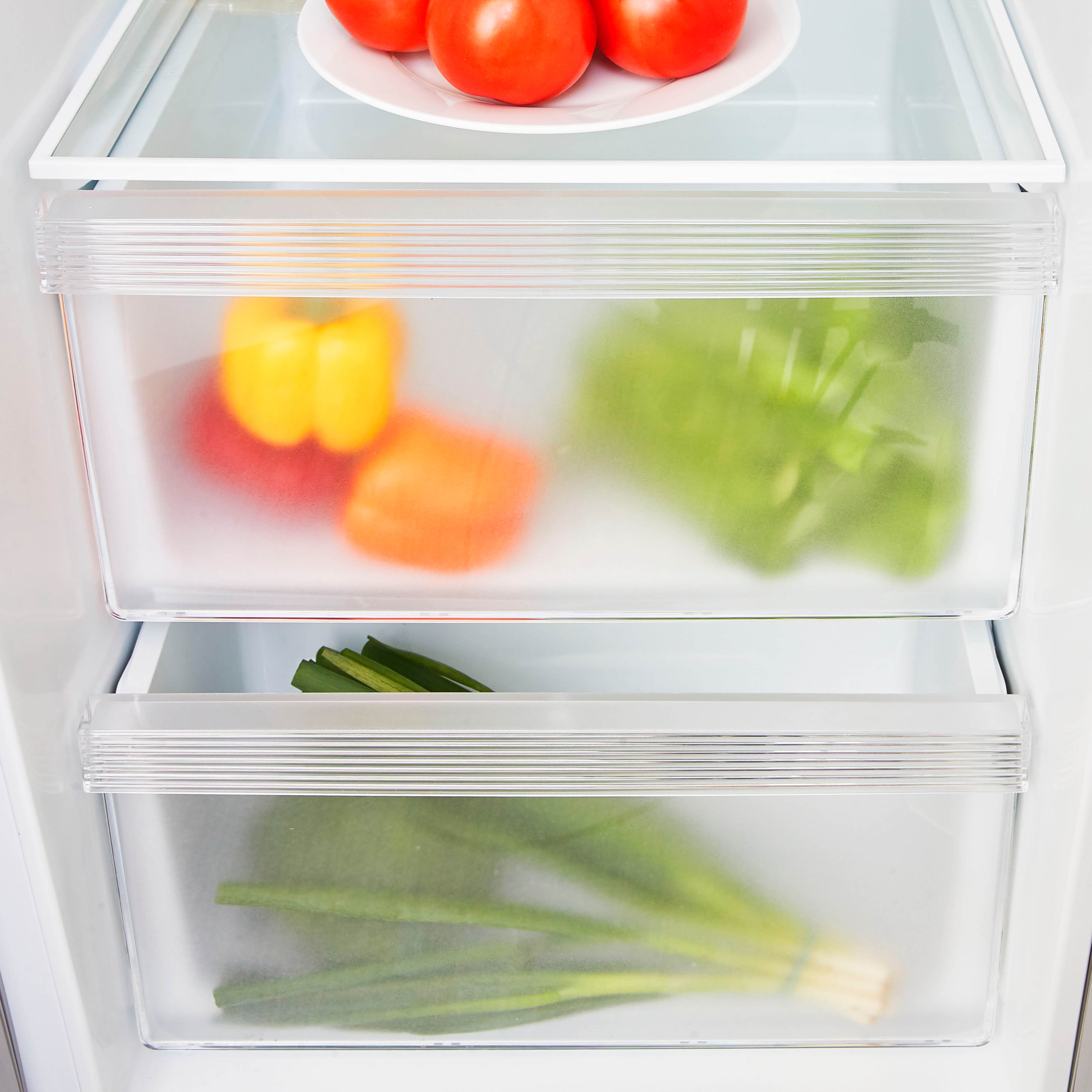 Refrigerator drawers with vegetables. Red, yellow peppers, green lettuce, and green onions.