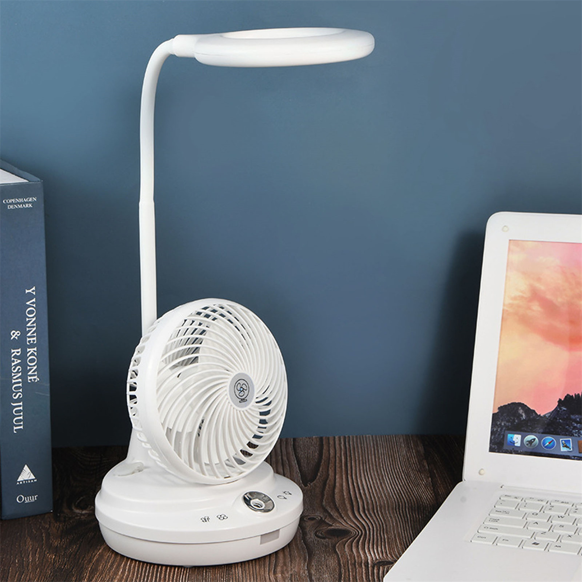 Weiße Schreibtischlampe mit Ventilator, Büchern und Laptop auf einem Holztisch.