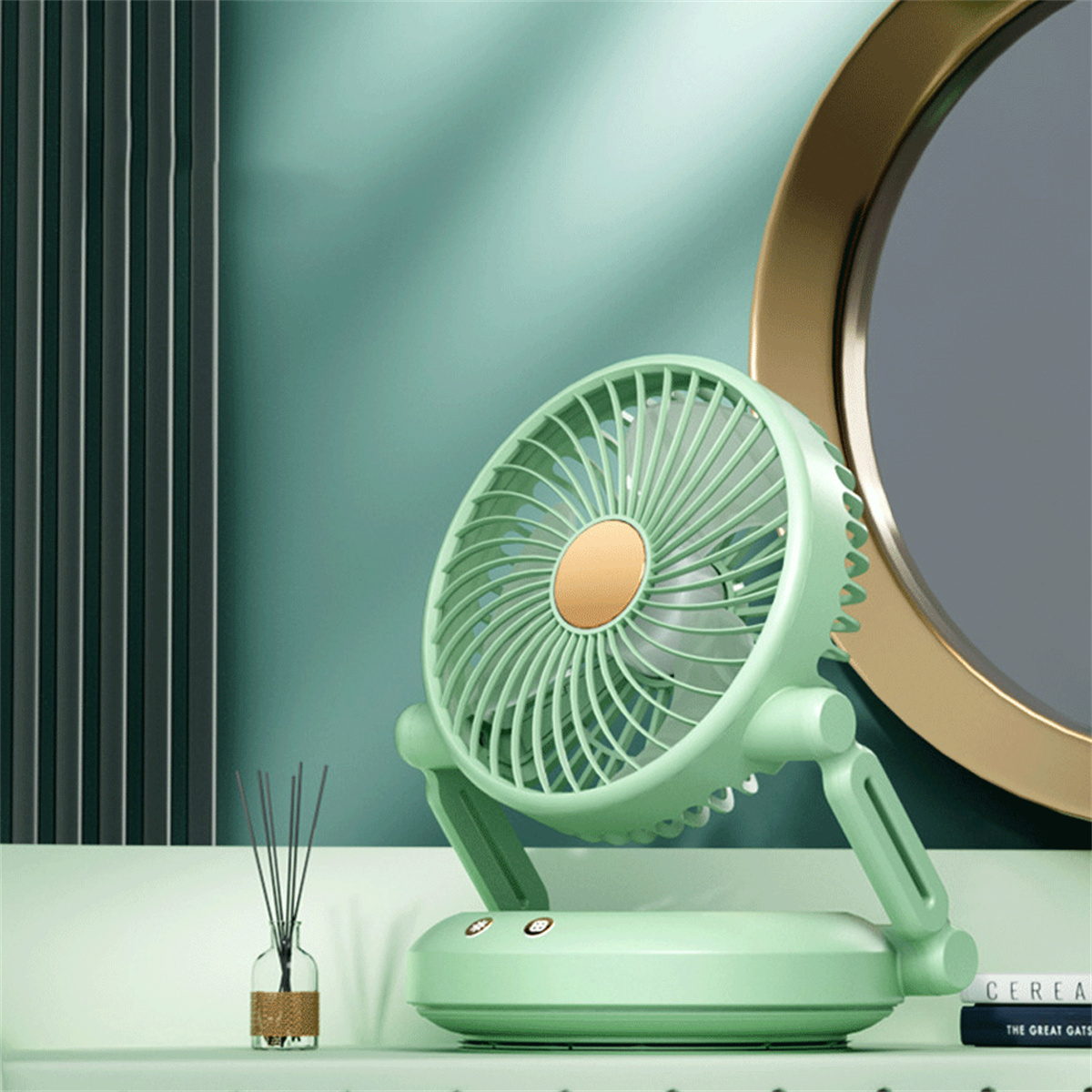 Ein mintgrüner Tischventilator mit verstellbarem Fuß, mit einer Vase und Spiegel im Hintergrund.