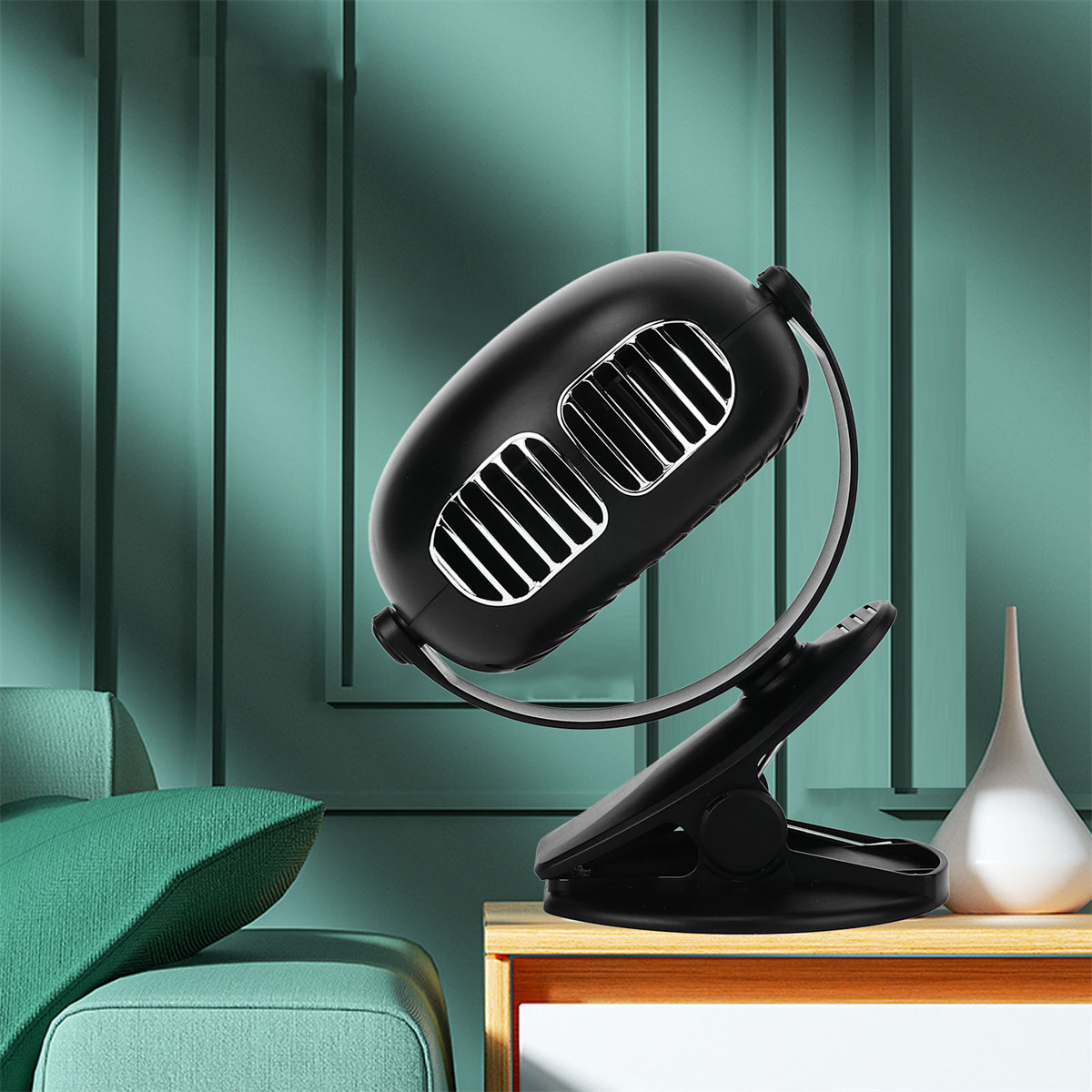 Ein schwarzer, oval geformter Ventilator mit silbernen Akzenten, montiert an einem Clip, steht auf einer Holzoberfläche.