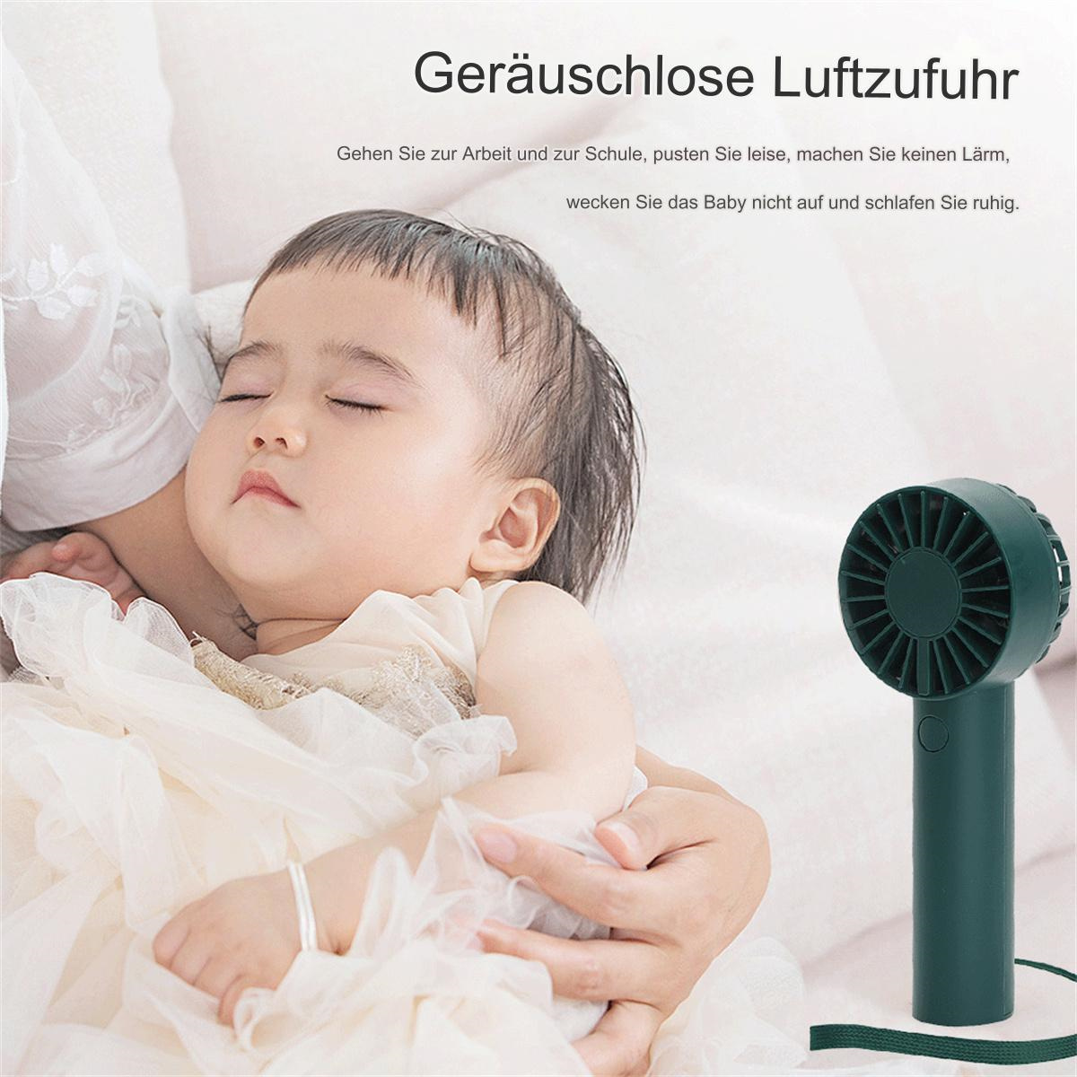 Ein Baby schläft in jemandes Armen, mit einem grünen tragbaren Ventilator im Vordergrund.