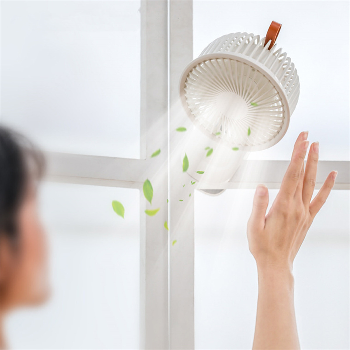 Eine Person in der Nähe des Ventilators, wobei Blätter aus ihm herauswehen.