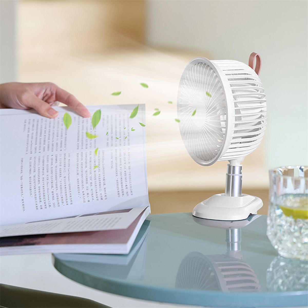 Die Hand einer Person in der Nähe eines Ventilators und eines offenen Buches.
