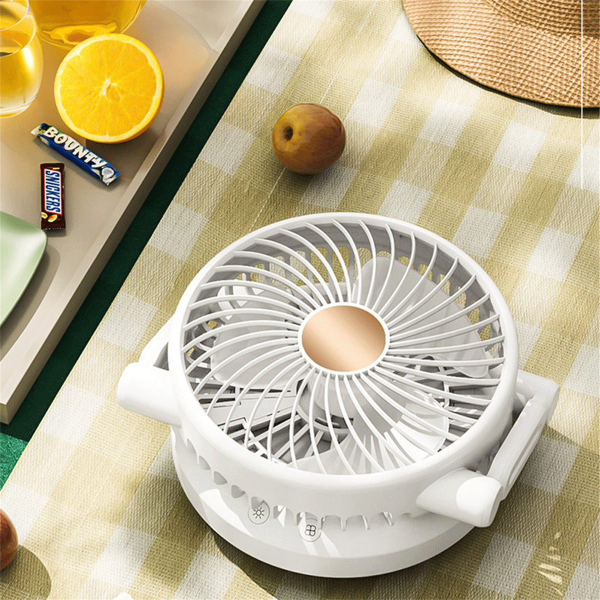Weißer tragbarer Ventilator auf Picknickdecke. Snacks und Getränke an den Seiten.
