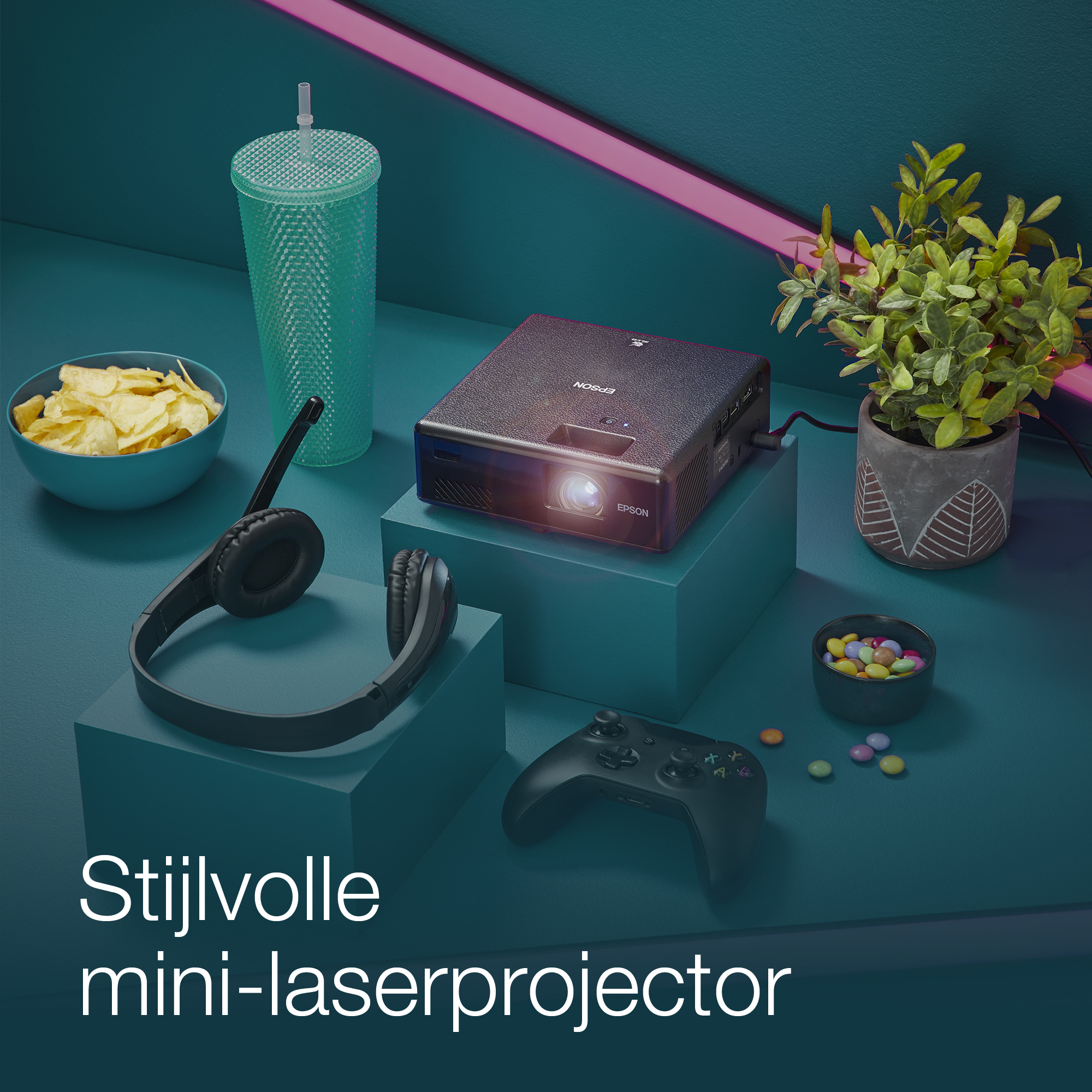 Un proiettore con accessori su una superficie blu e verde acqua, con il testo 'Stijlvolle mini-laserprojector'.