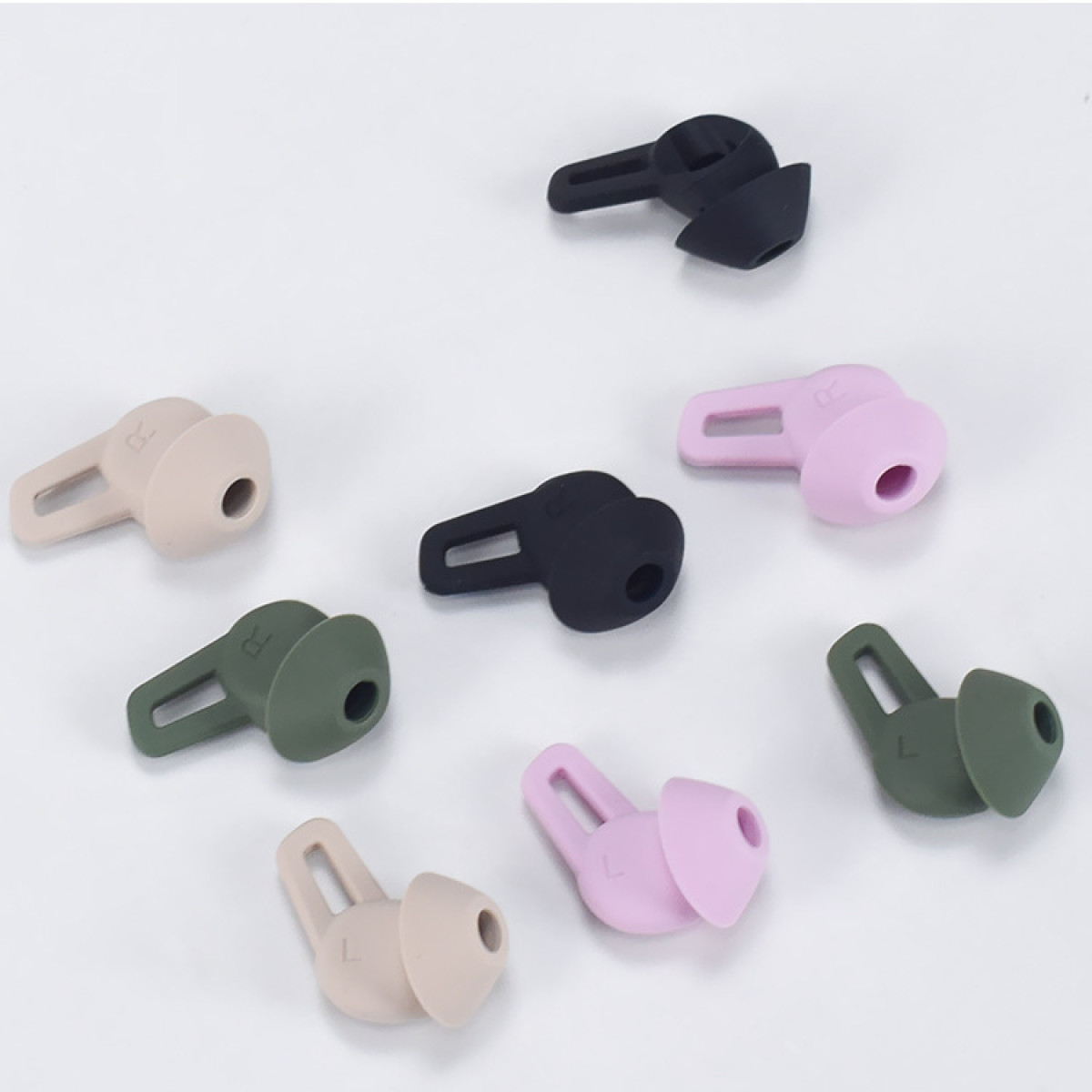 Verschiedene farbige Ohrstöpsel für Ohrhörer, in Farben wie Beige, Schwarz, Grün und Rosa, auf einer Oberfläche angeordnet.