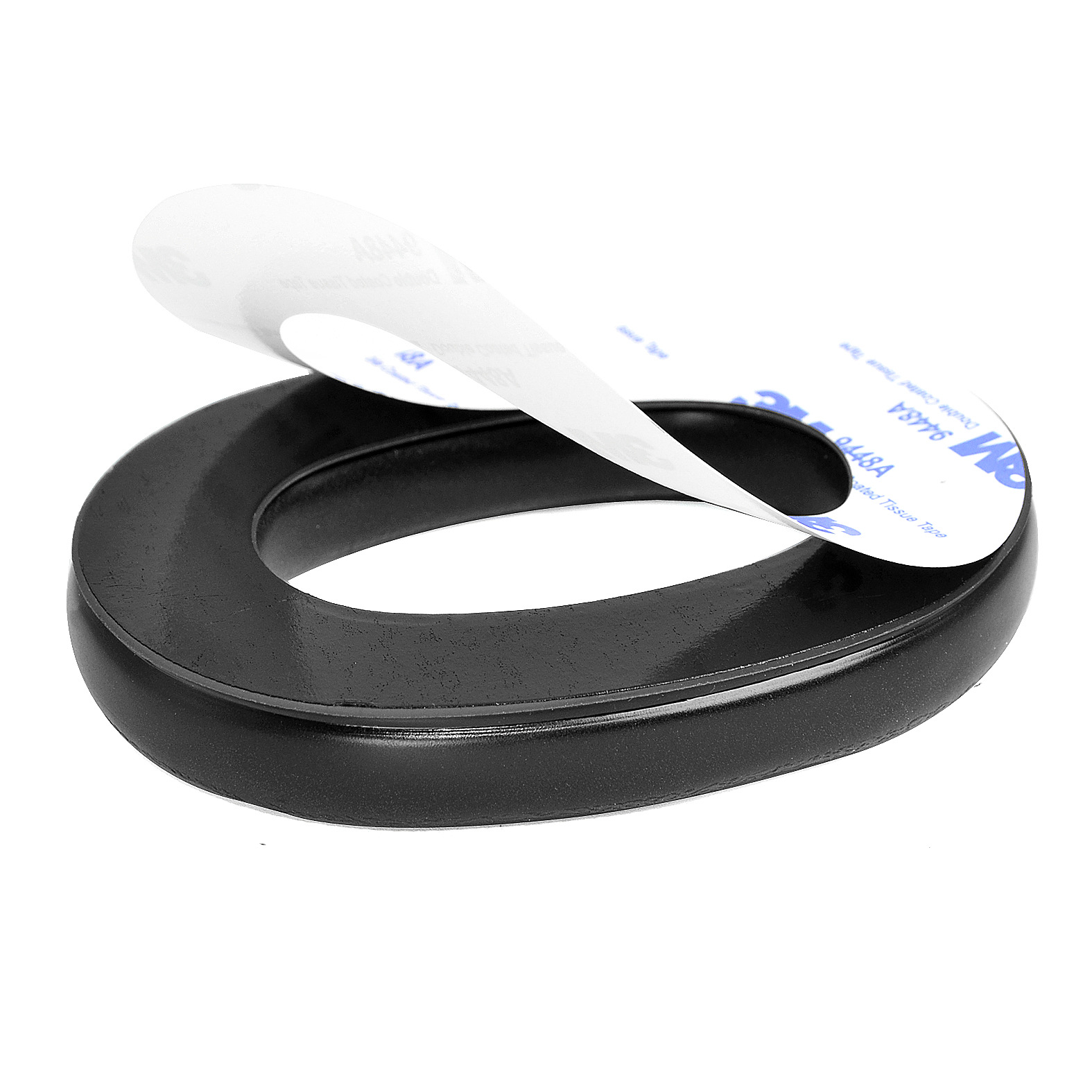 Ein schwarzes, ovales Ohrpolster mit einem weißen Etikett, ein Teil des doppelseitigen Klebebands ist sichtbar.