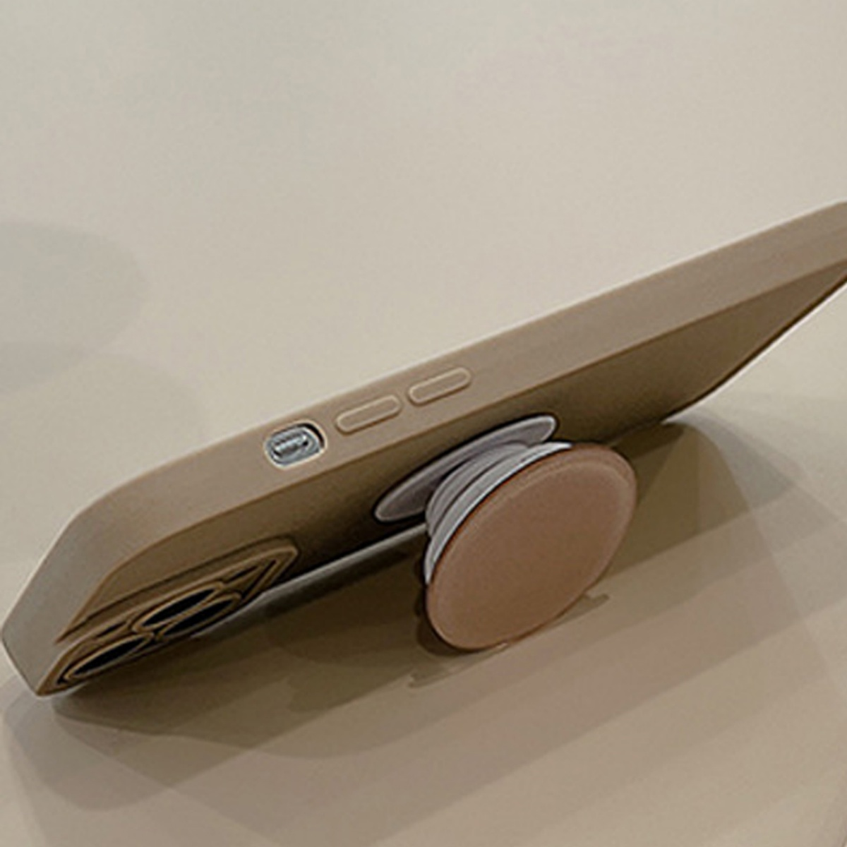 Eine Handyhülle mit Pop-up-Griff. Die Hülle ist beige. Der Hintergrund ist Tisch.