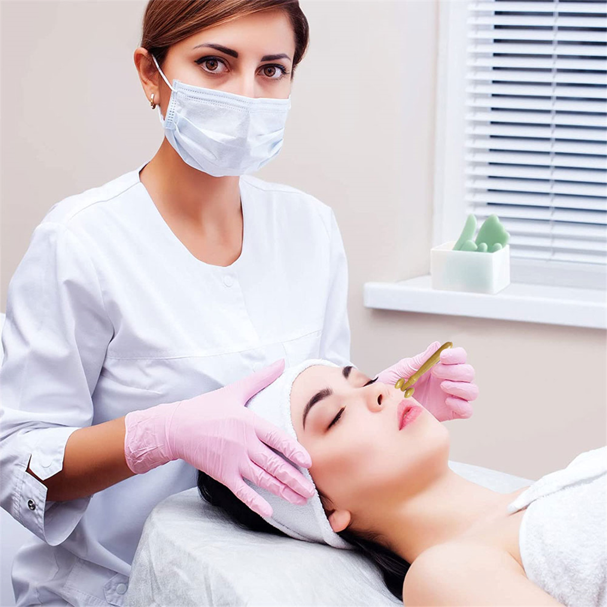 Eine Frau mit Maske führt eine Gesichtsbehandlung durch. Der Patient liegt auf einem Bett.