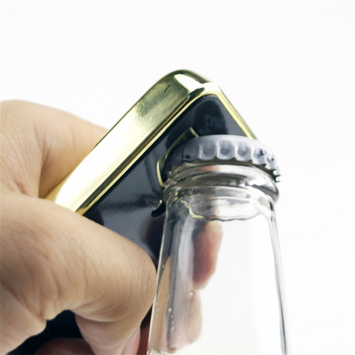 Hand öffnet eine Flasche mit einem gold-schwarzen Flaschenöffner. Weißer Hintergrund.