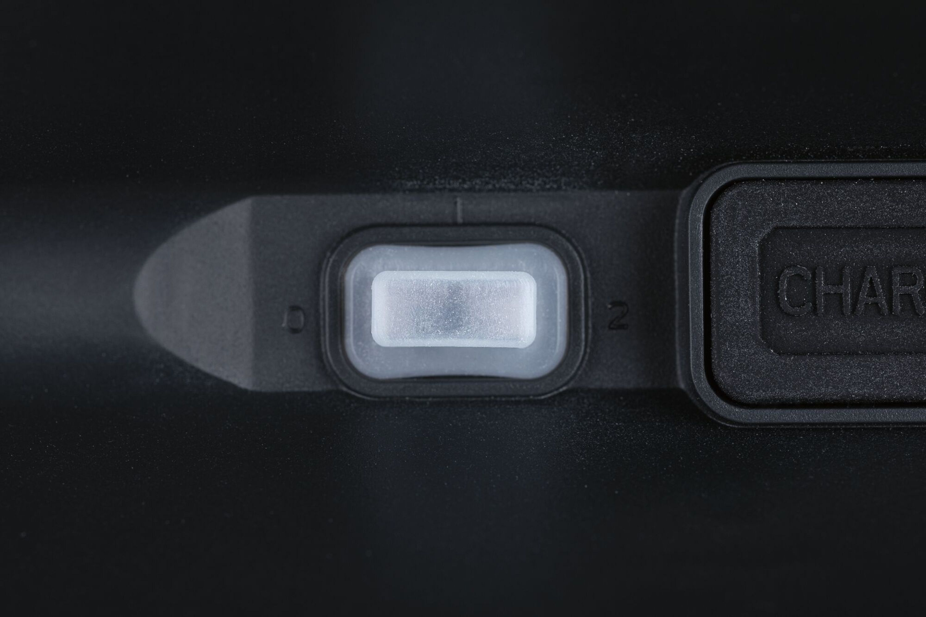 Zbliżenie czarnego urządzenia z prostokątnym przyciskiem zasilania i cyfrą '2'.