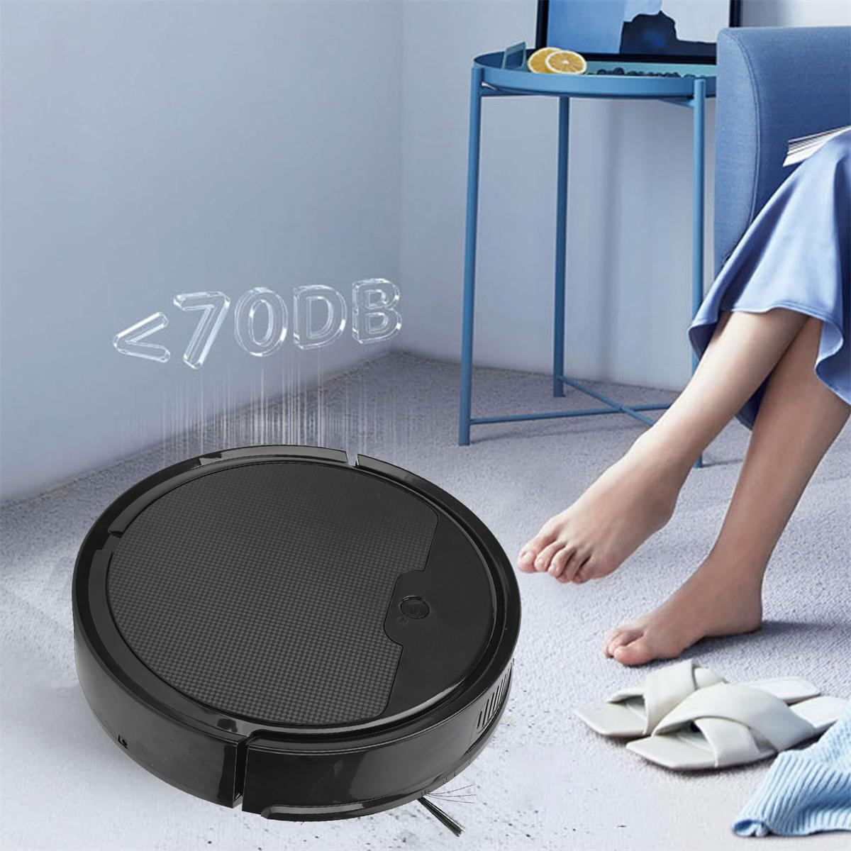 Schwarzer Roboter-Staubsauger auf einem Boden. Text: <lt/>70DB. Füße einer Frau und eine blaue Wand im Hintergrund.