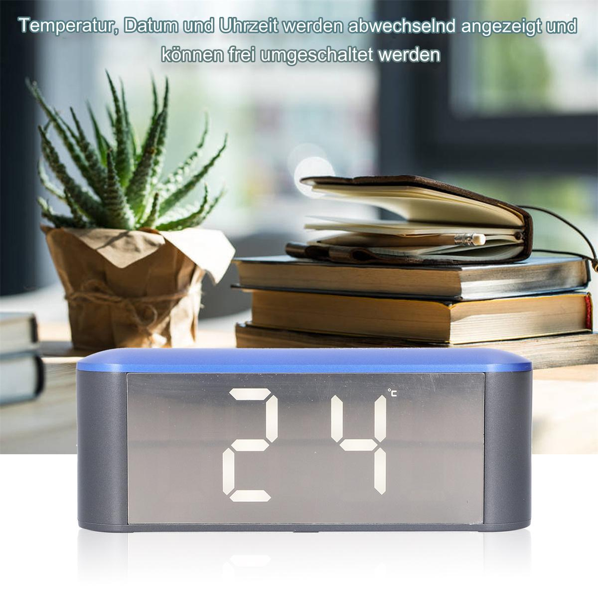 Digitaluhr zeigt 24°C. Eine kleine Pflanze links. Bücher und ein Notizbuch im Hintergrund.