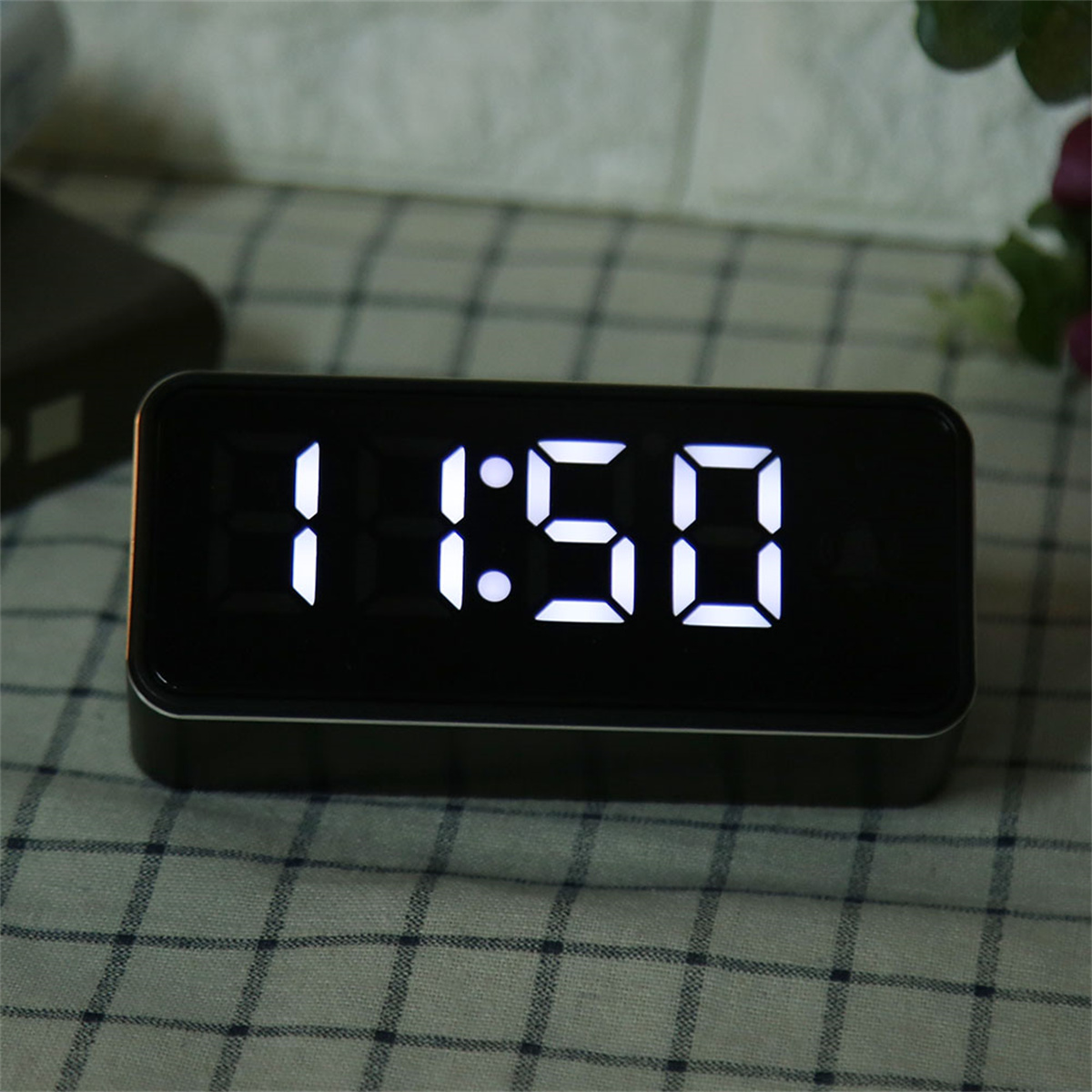Eine Digitaluhr zeigt 11:50 in weißen Ziffern an. Sie befindet sich auf einer gemusterten Oberfläche.