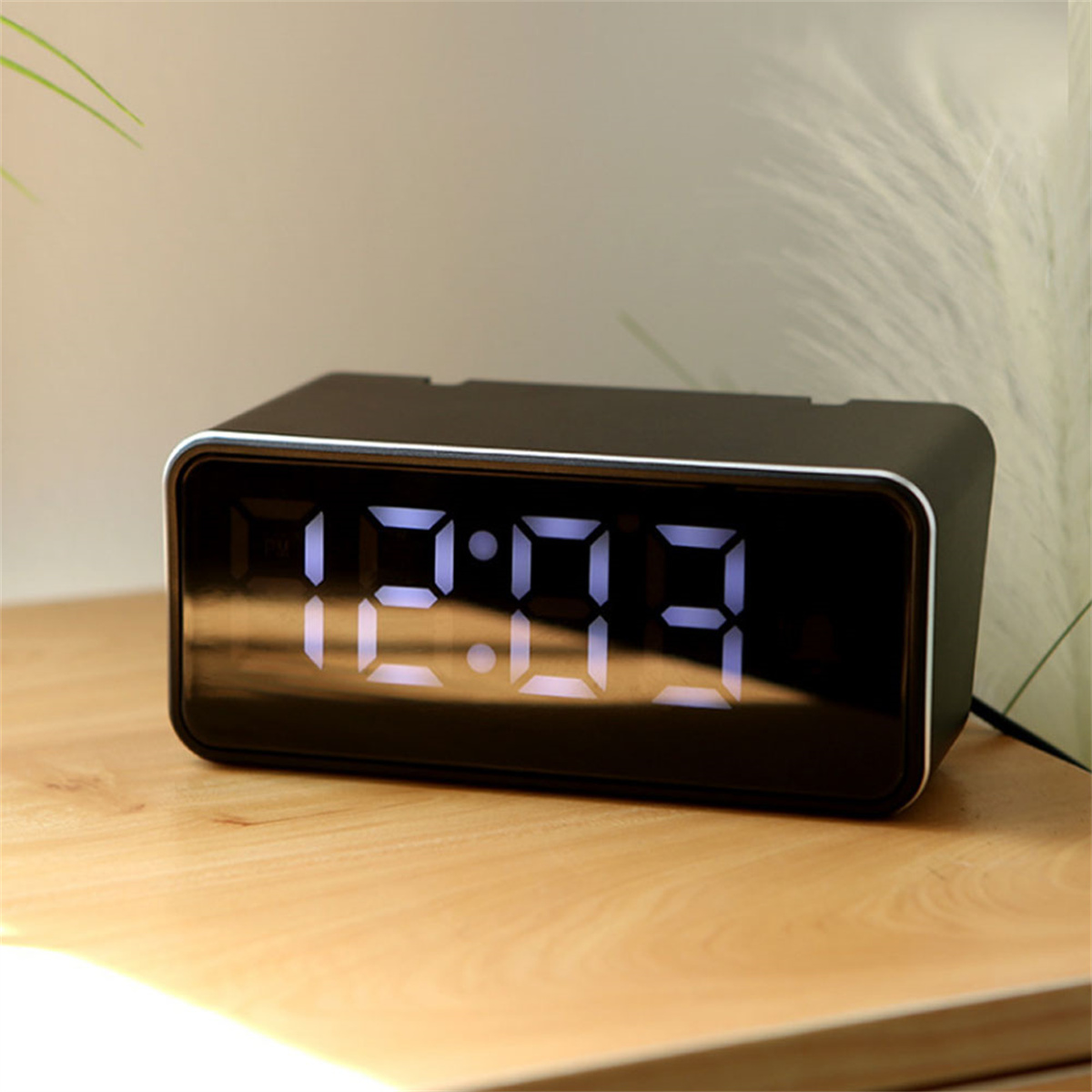 Schwarze Digitaluhr mit 12:03. Anzeige auf Holzoberfläche. Weiches Licht.