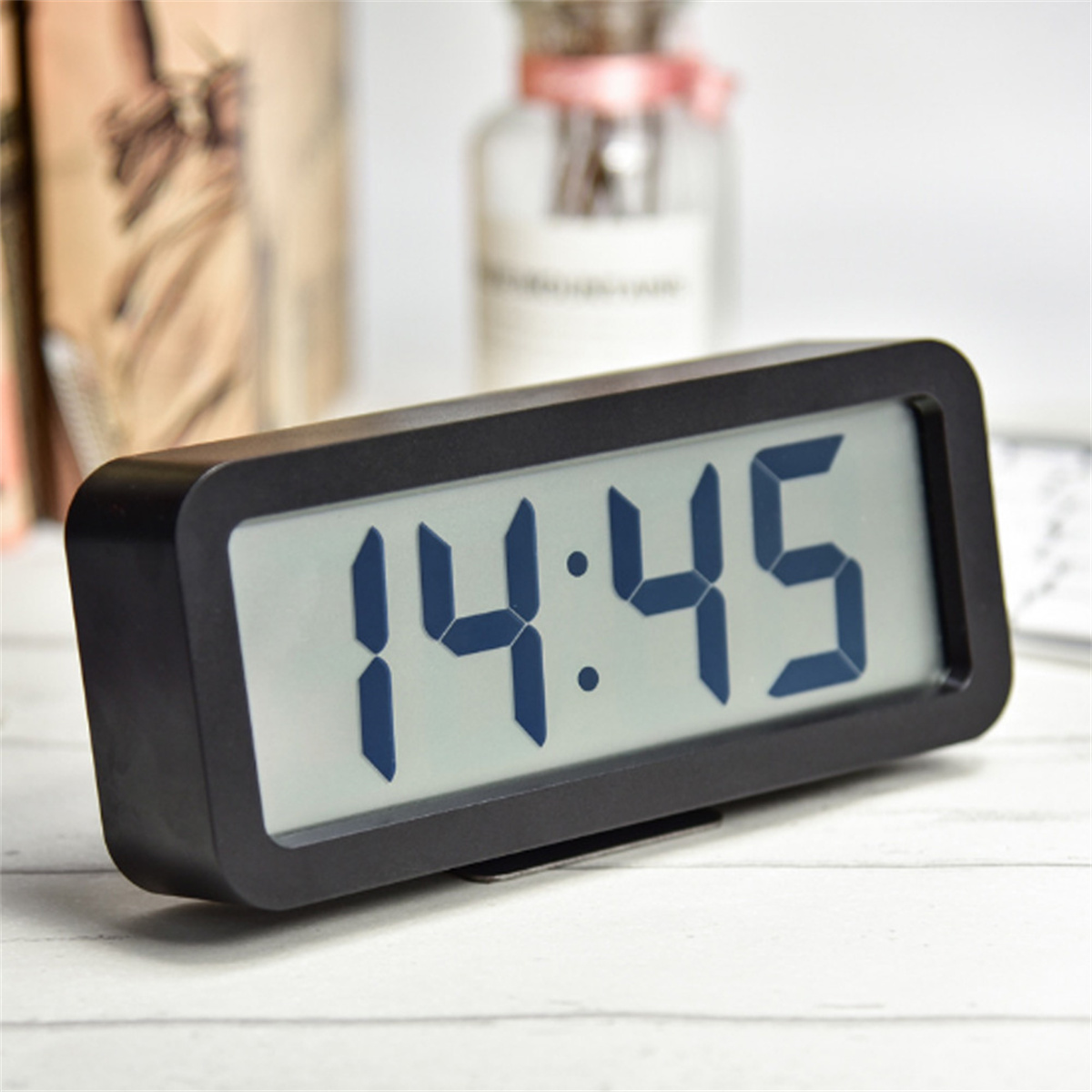 Eine schwarze Digitaluhr, die 14:45 anzeigt. Die Uhr steht auf einer hellen Holzoberfläche.