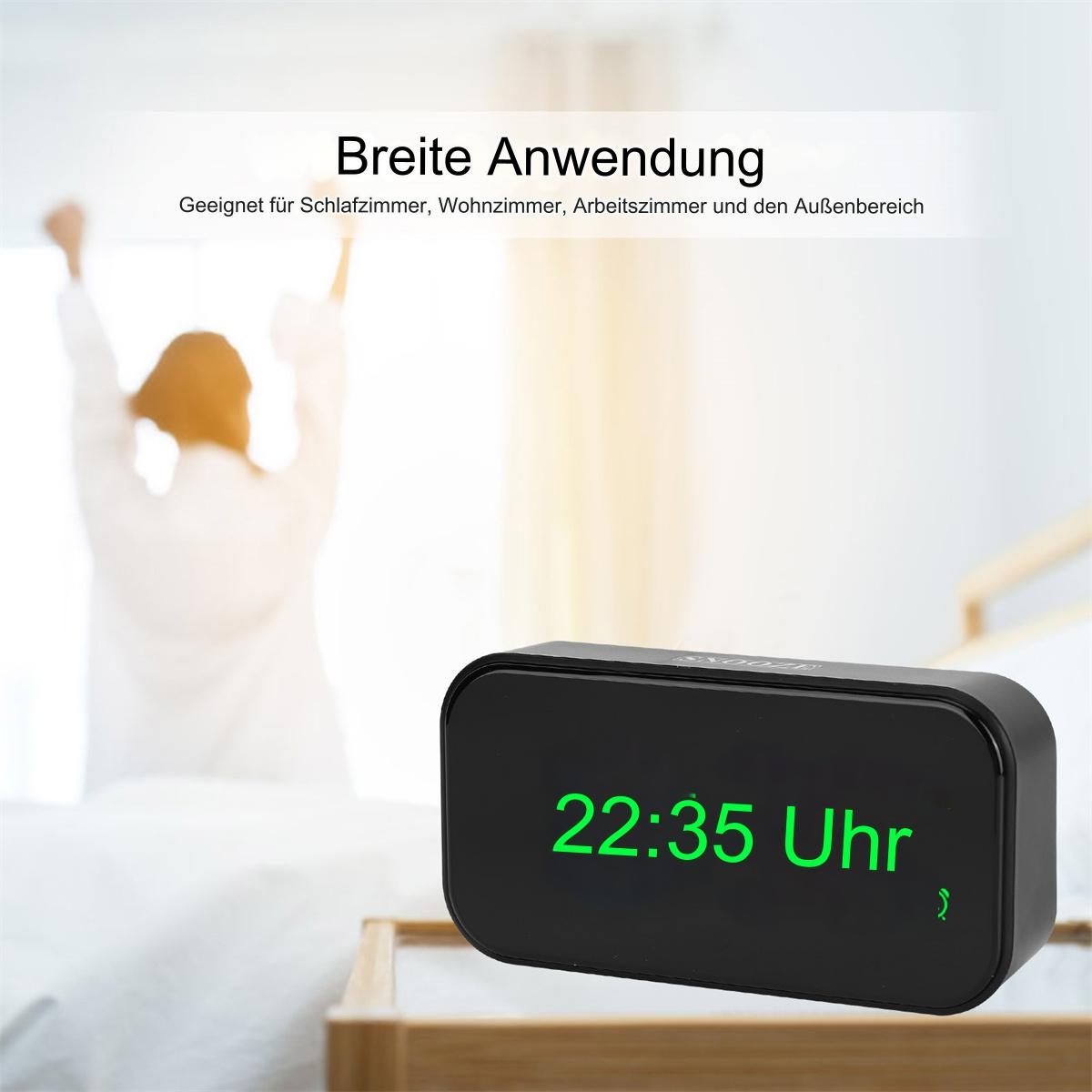 Schwarze Digitaluhr zeigt 22:35. Person im weißen Bademantel im Hintergrund.