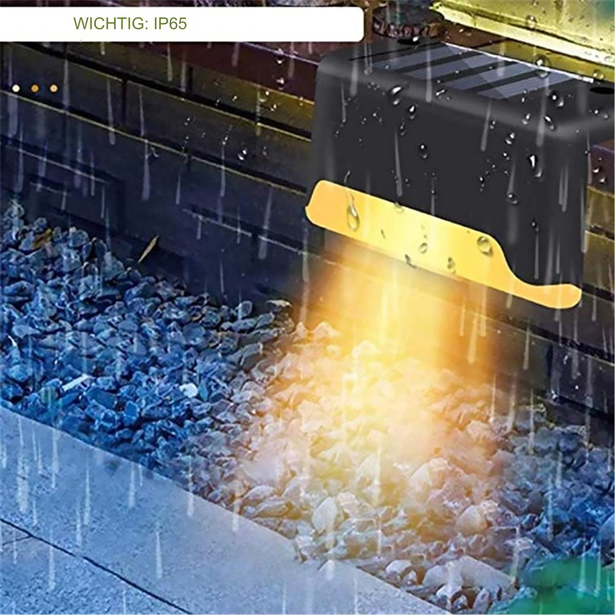 Ein schwarzes Außenlicht mit goldenem Akzent, das auf Steine scheint. Das Licht ist IP65-zertifiziert.