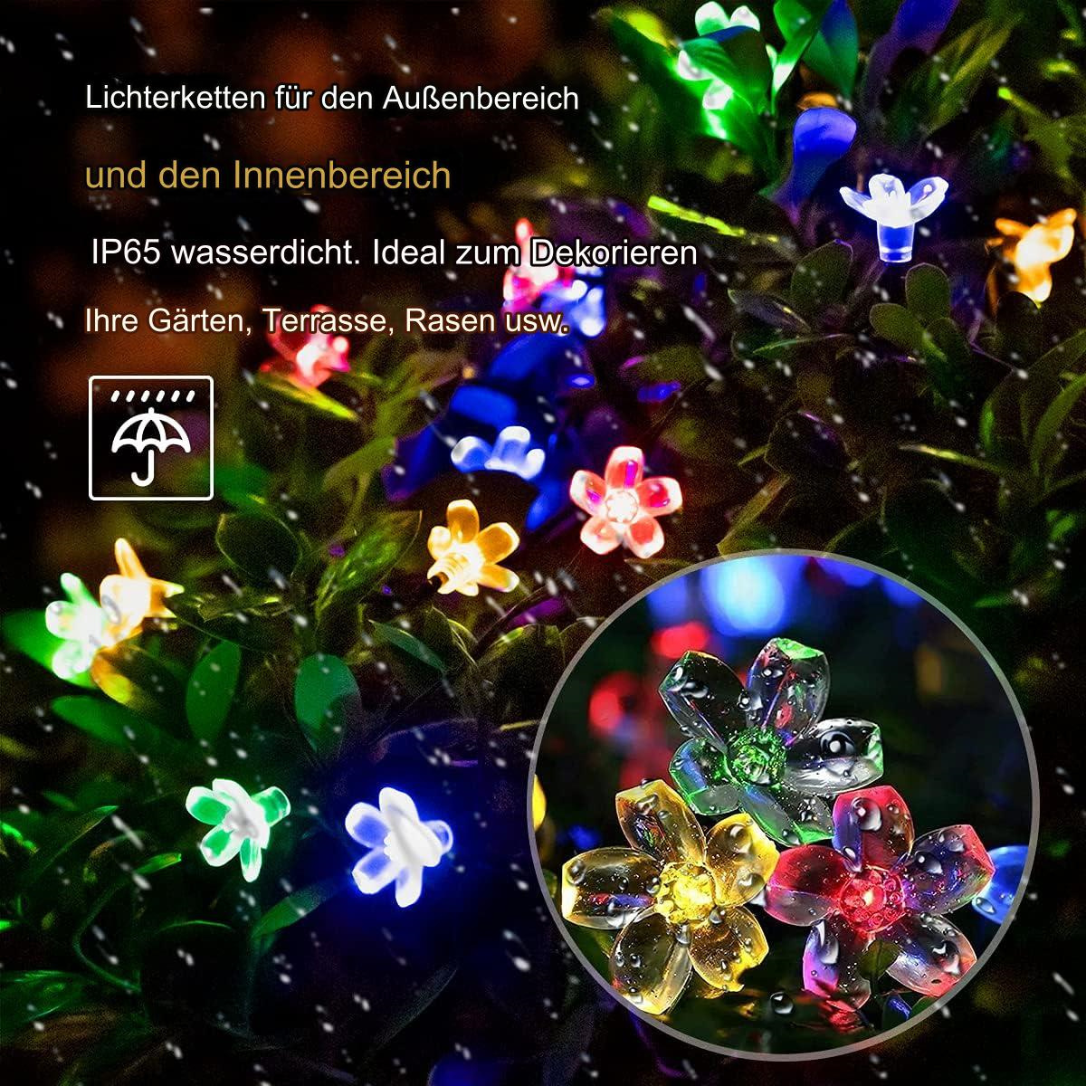 Blütenförmige Lichterketten in einem Garten, mit Nahaufnahme der Lichter und Wassertropfen.