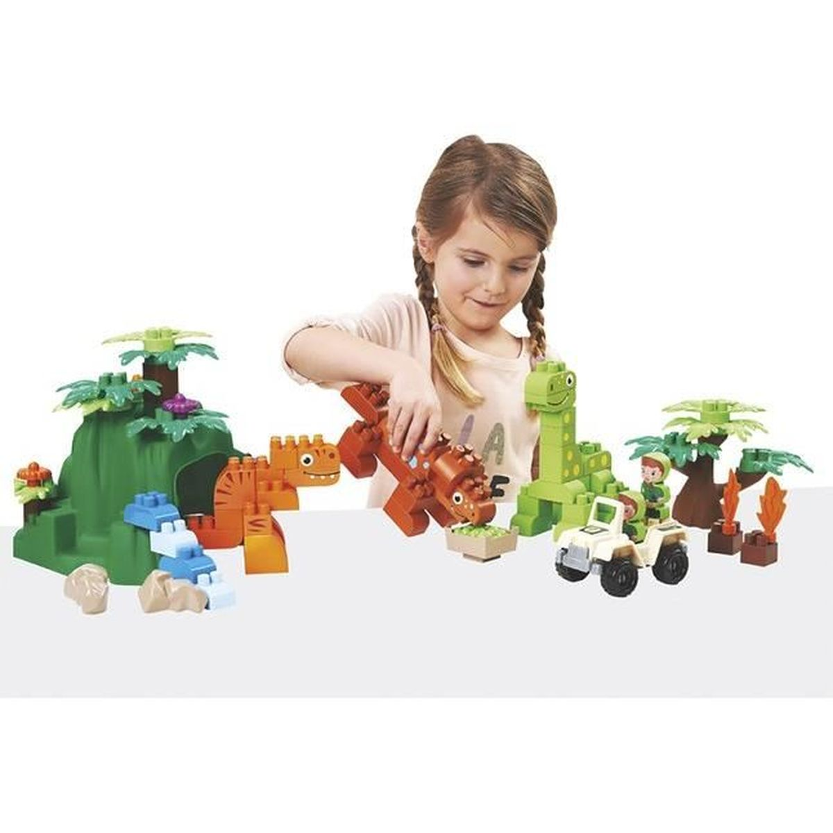 Ein Mädchen spielt mit Dinosaurier-Bausteinen und baut eine Szene mit einem Jeep und Bäumen zusammen.