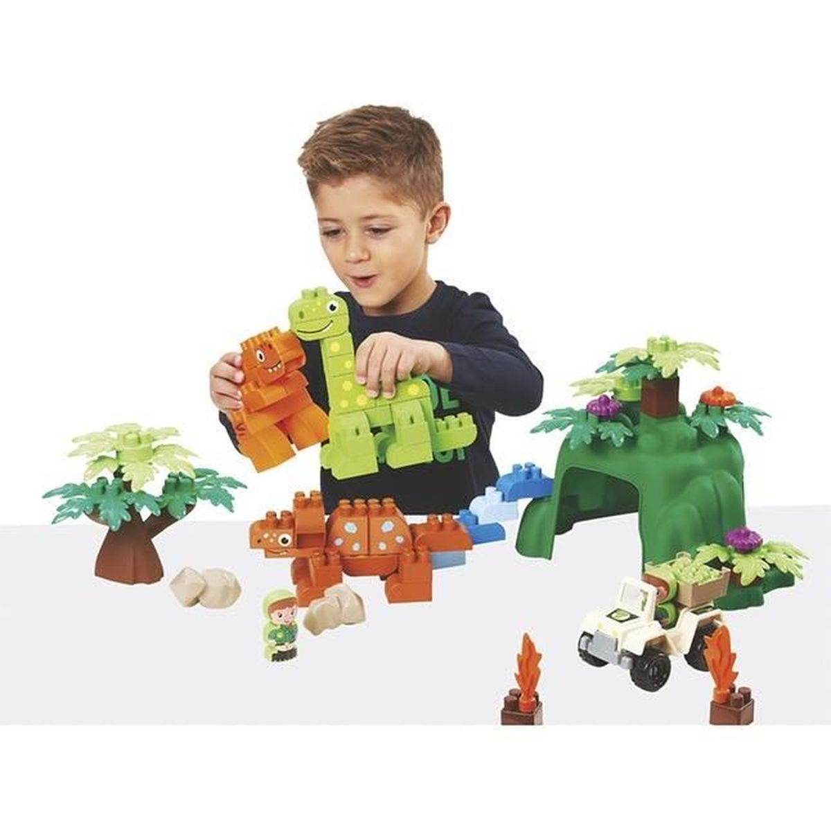 Ein Junge spielt mit Dinosaurier-Bausteinen und arrangiert eine Szene mit einem Jeep und Bäumen.