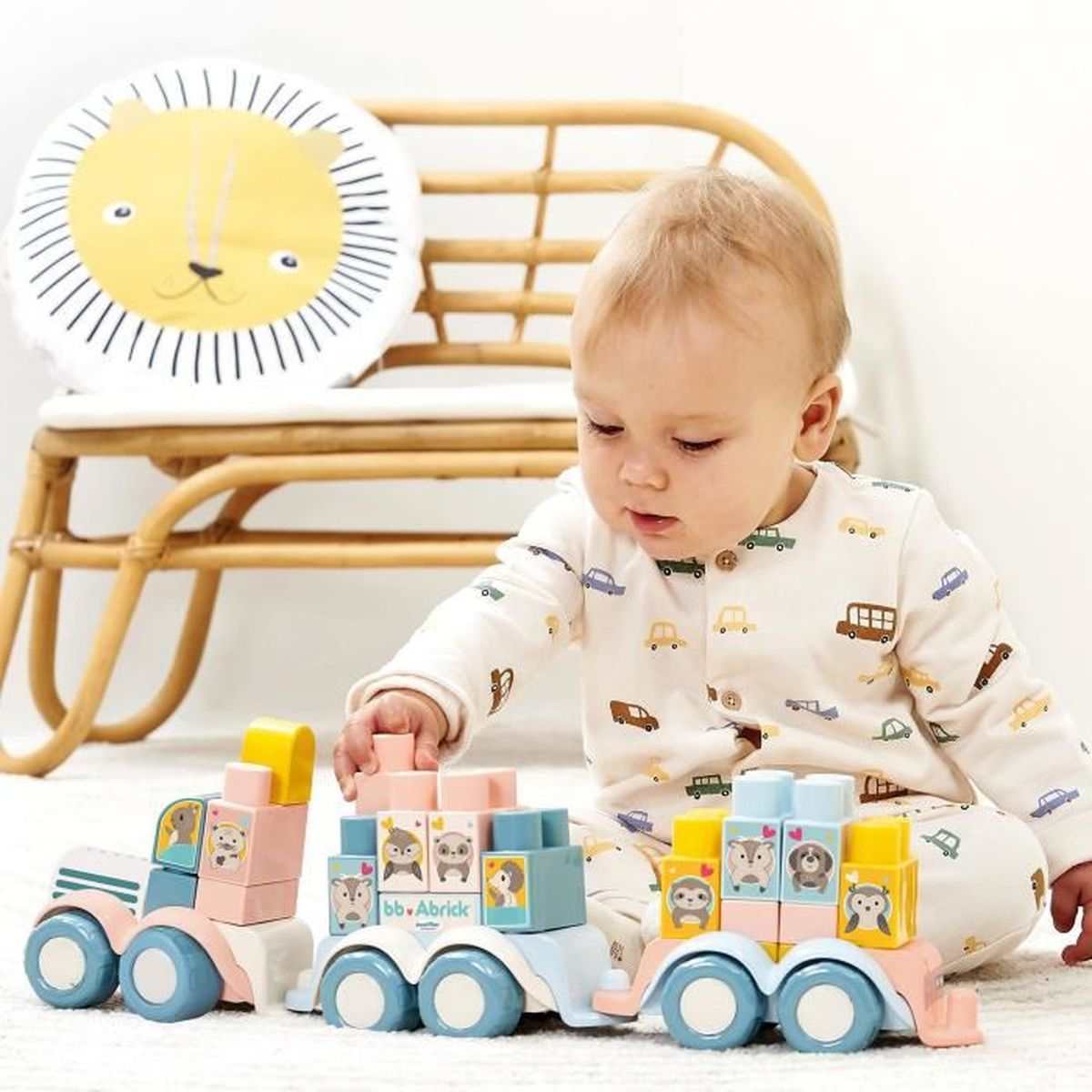 Bambino che gioca con trenini giocattolo di legno colorati. Un cuscino a forma di leone sullo sfondo.