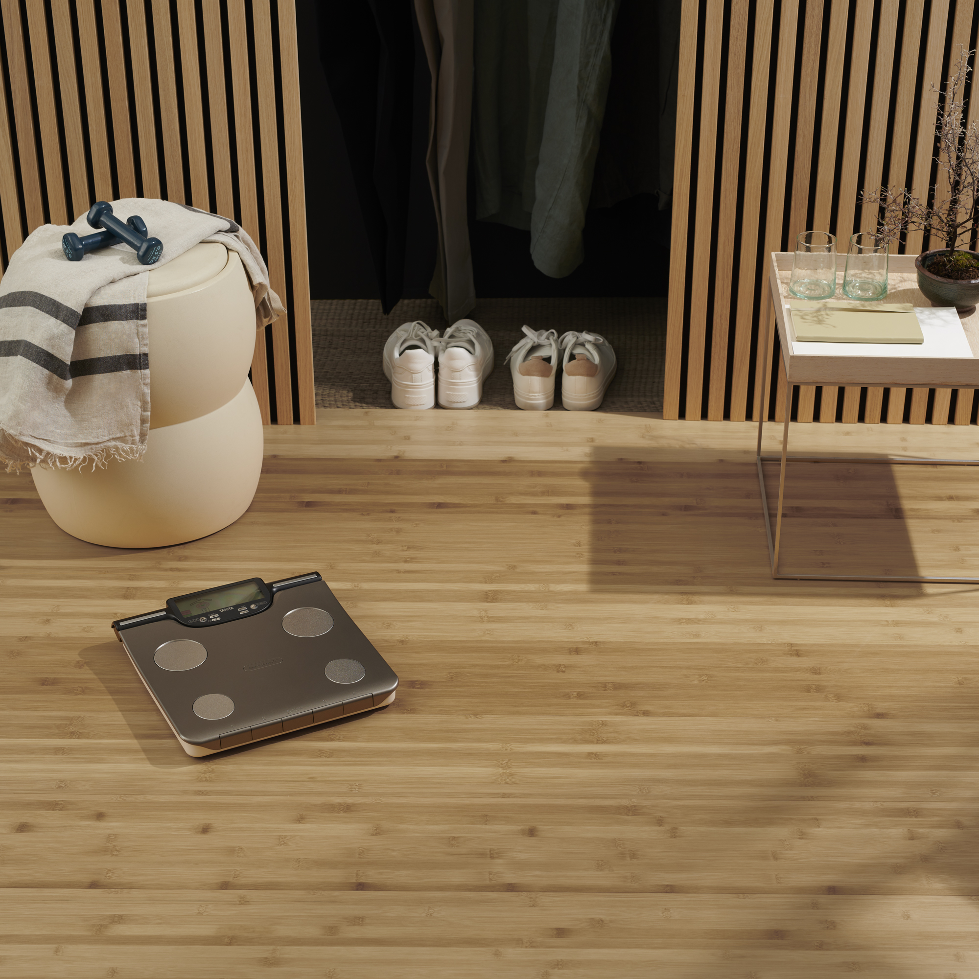 Weegschaal op de vloer, met schoenen, handdoeken en halter op een plank.