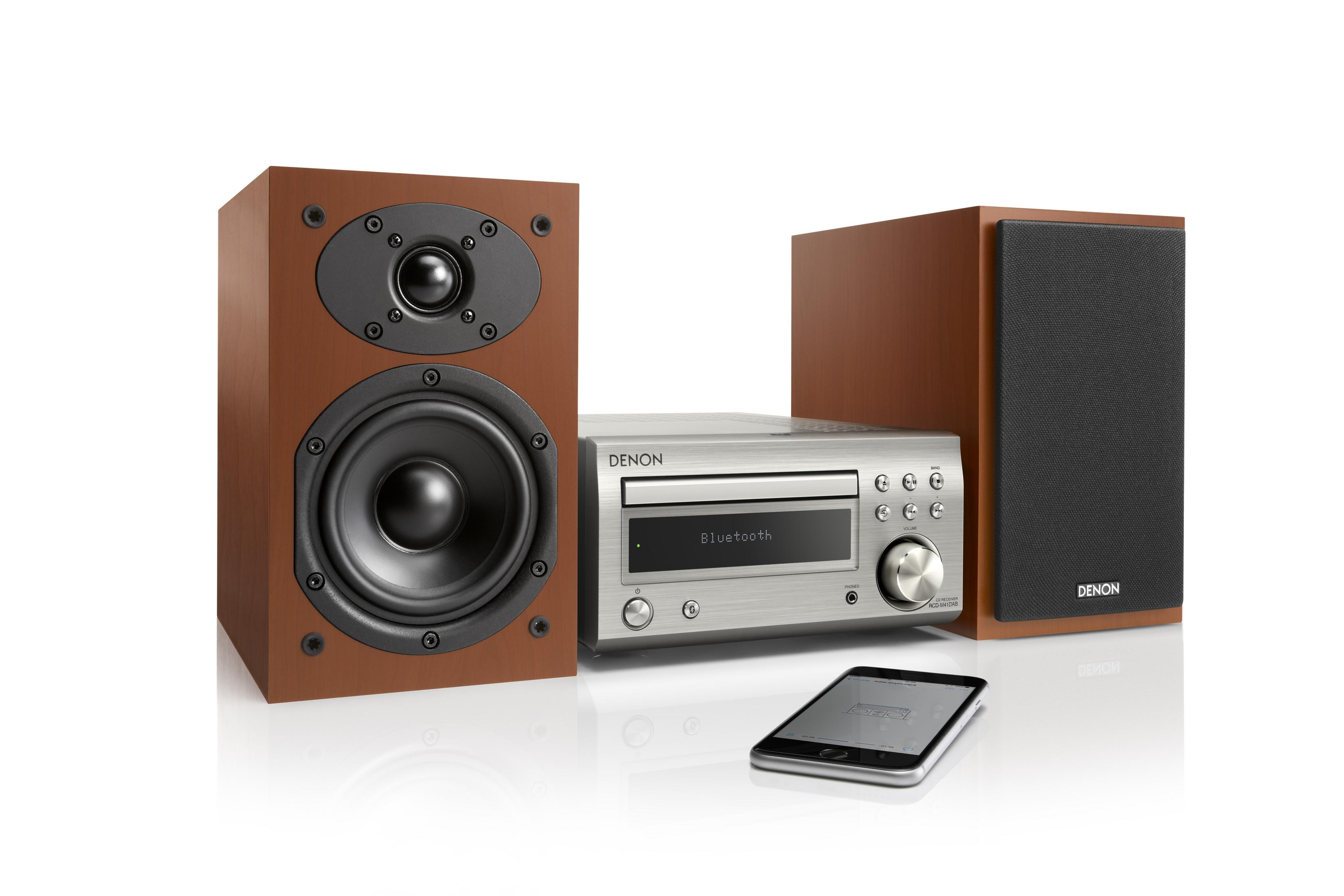 Un sistema stereo Denon con due altoparlanti, un'unità centrale e un telefono cellulare sul tavolo.