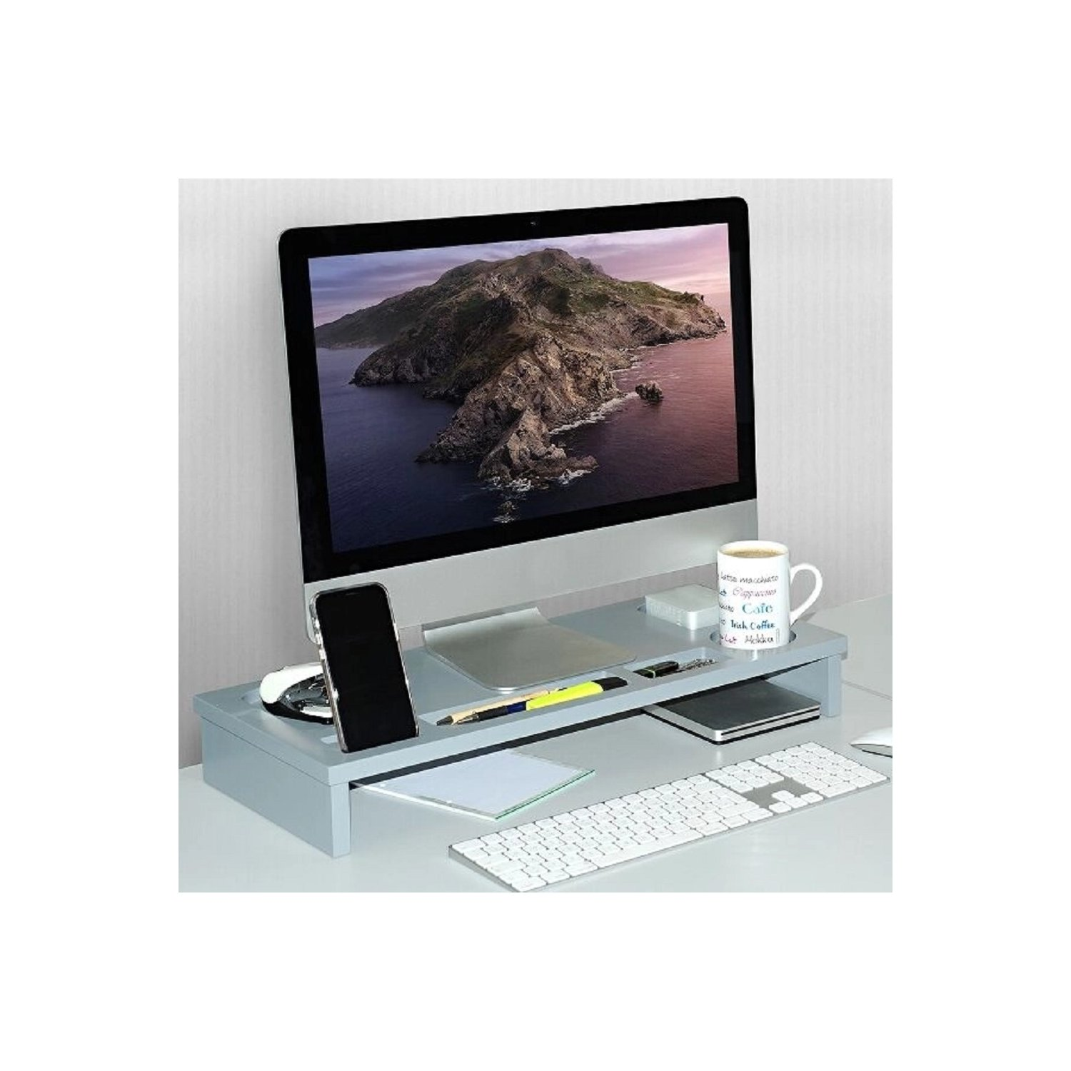 Ein Computermonitor auf einem Erhöher mit Tastatur, Maus, Telefon und Tasse auf einem Schreibtisch. Bergszene.