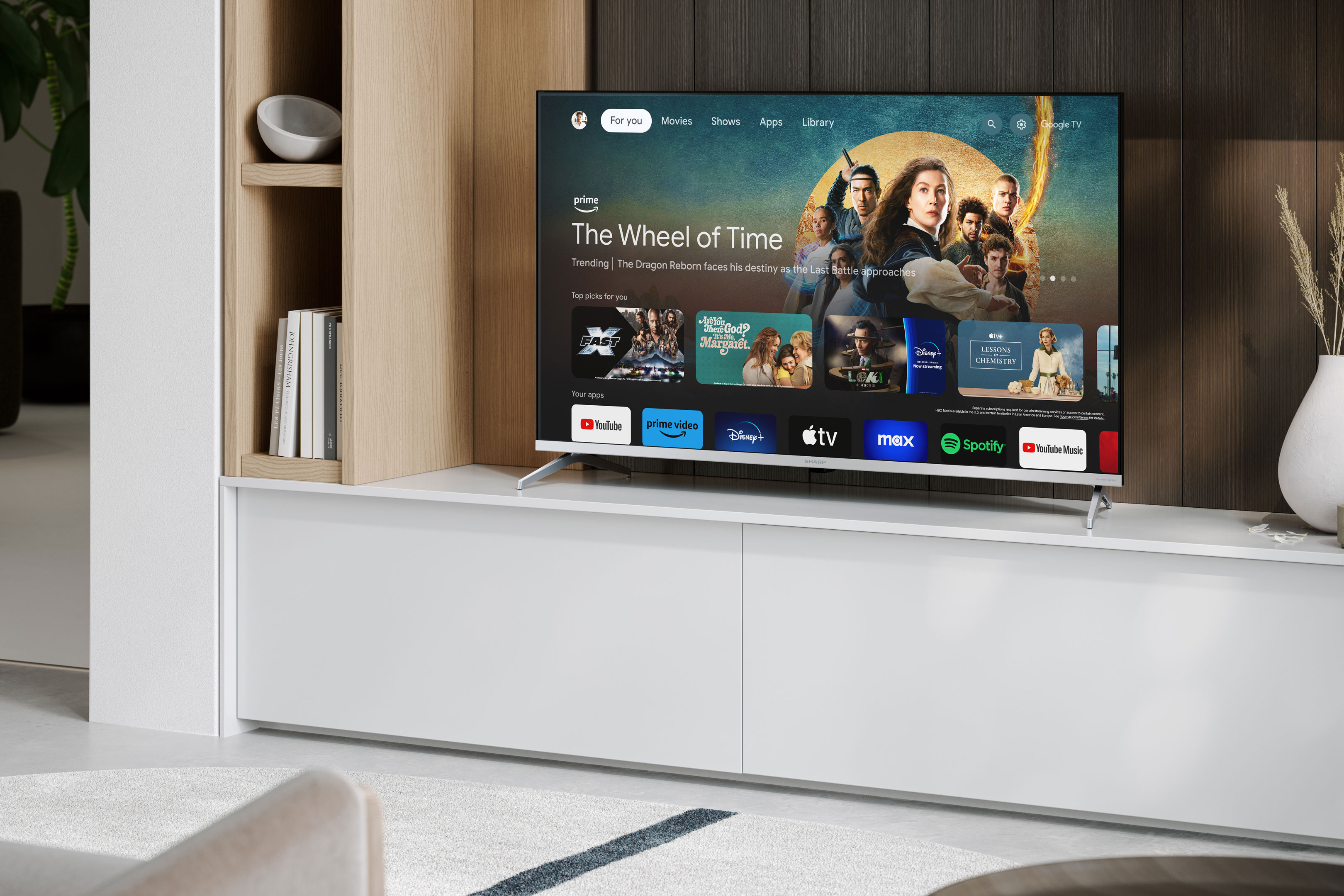 TV-Bildschirm mit einer Sendung und App-Symbolen. Weißer Schrank und Deko.