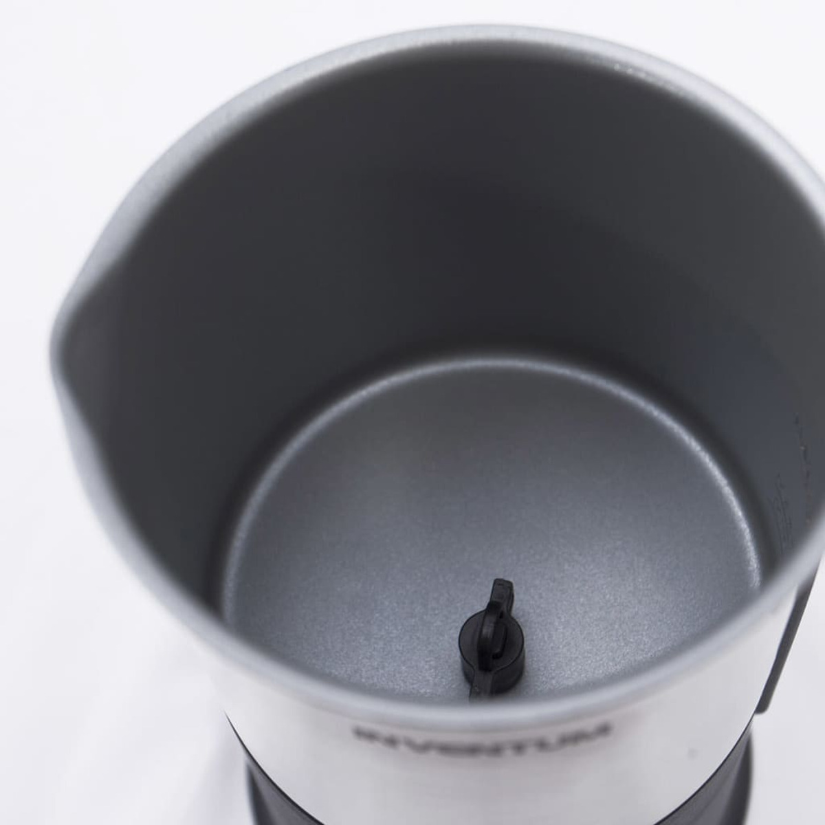 Close-up of a gray metal interior of a container, with a black plastic piece in the center.