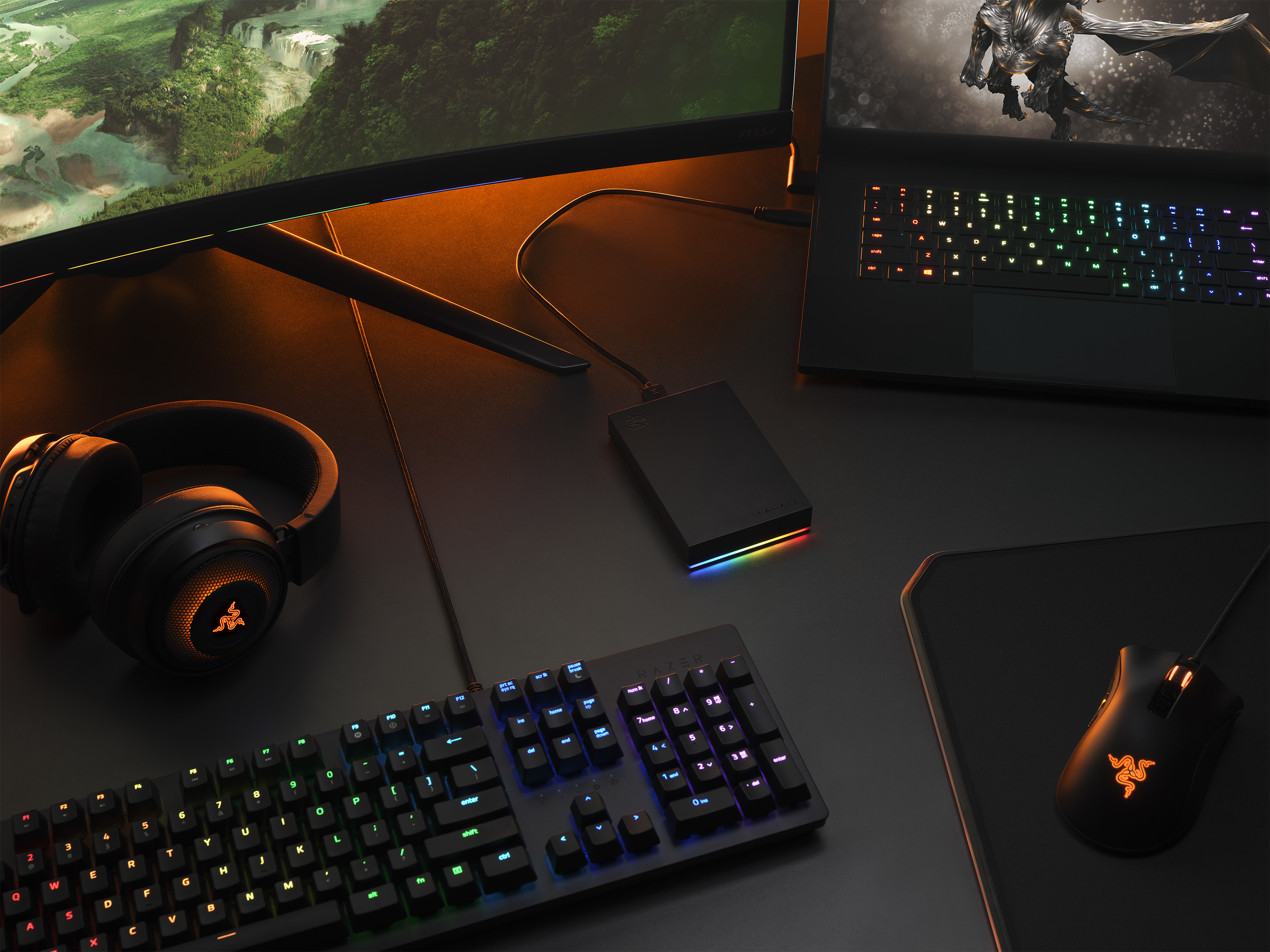 Gaming-Setup mit Monitor, Tastatur, Maus, Kopfhörern und Festplatte.
