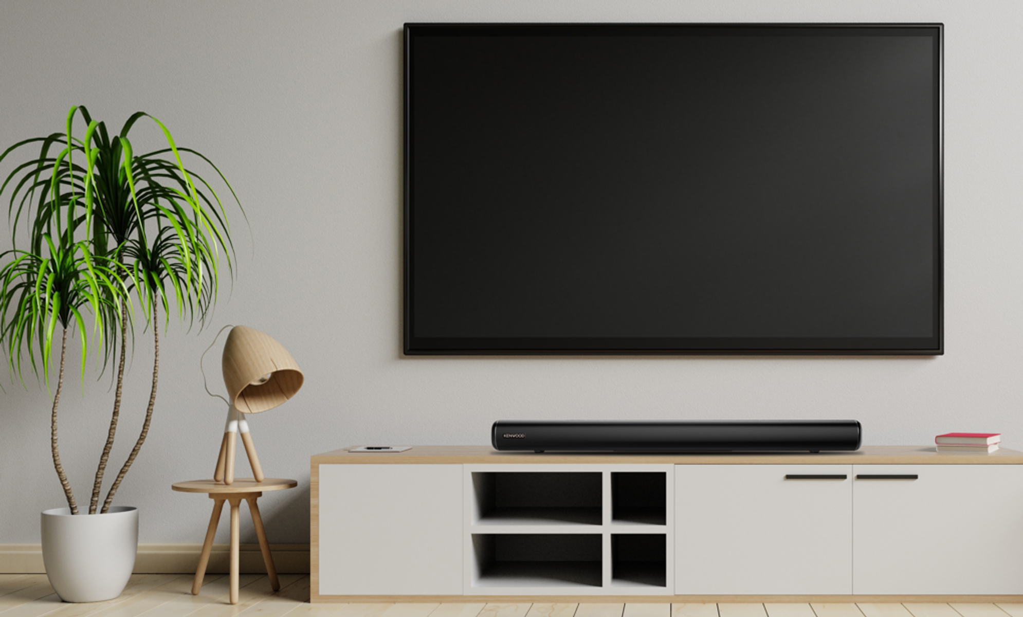 Una TV su un mobile bianco, soundbar sotto, con pianta e lampada.