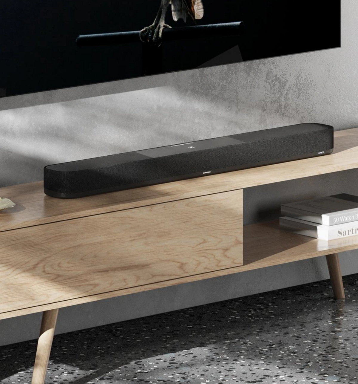 Schwarze Soundbar auf einem Holzschrank. Ein Fernseher befindet sich darüber.