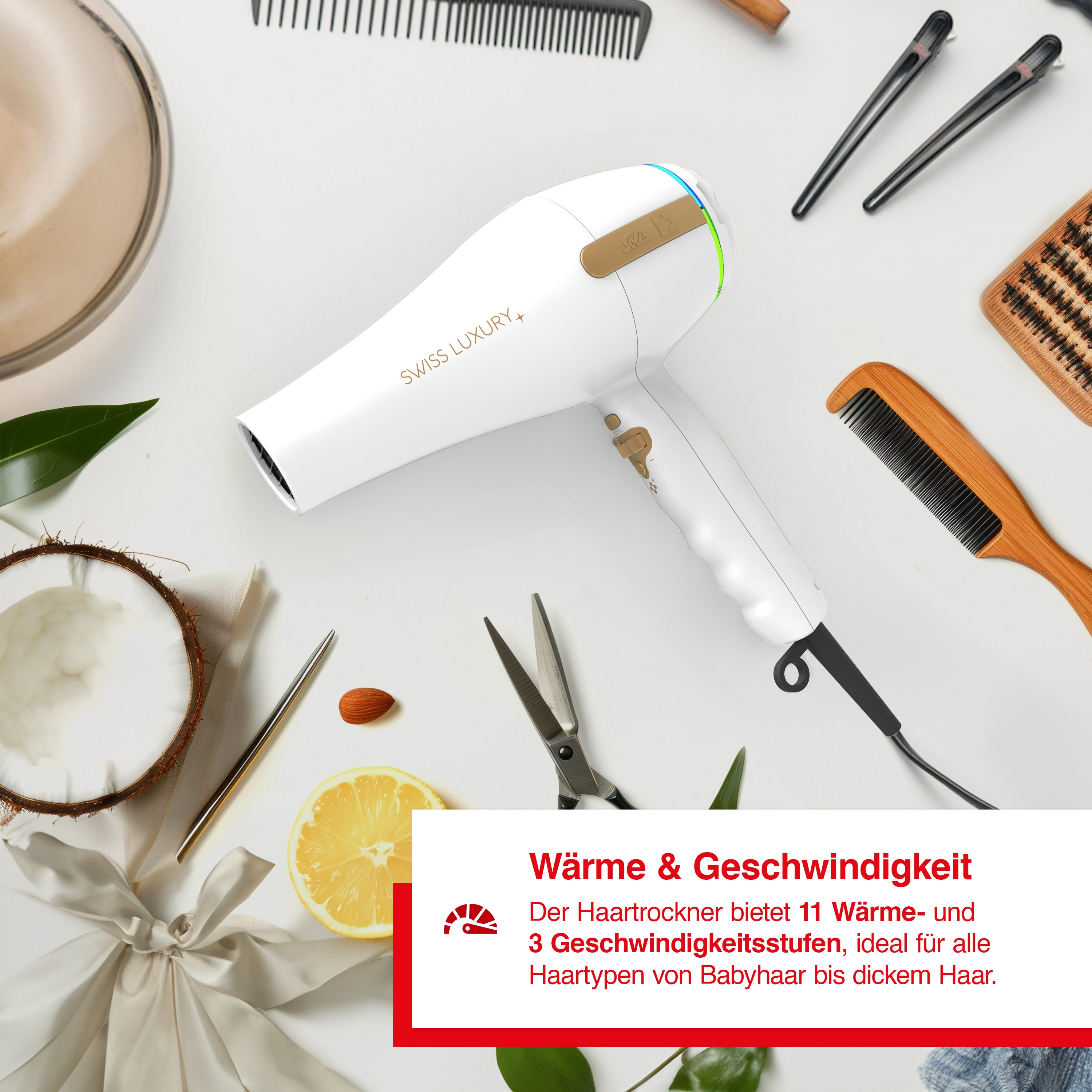 Ein weißer Haartrockner mit schwarzem Kabel und Haarstyling-Werkzeugen auf weißer Oberfläche.