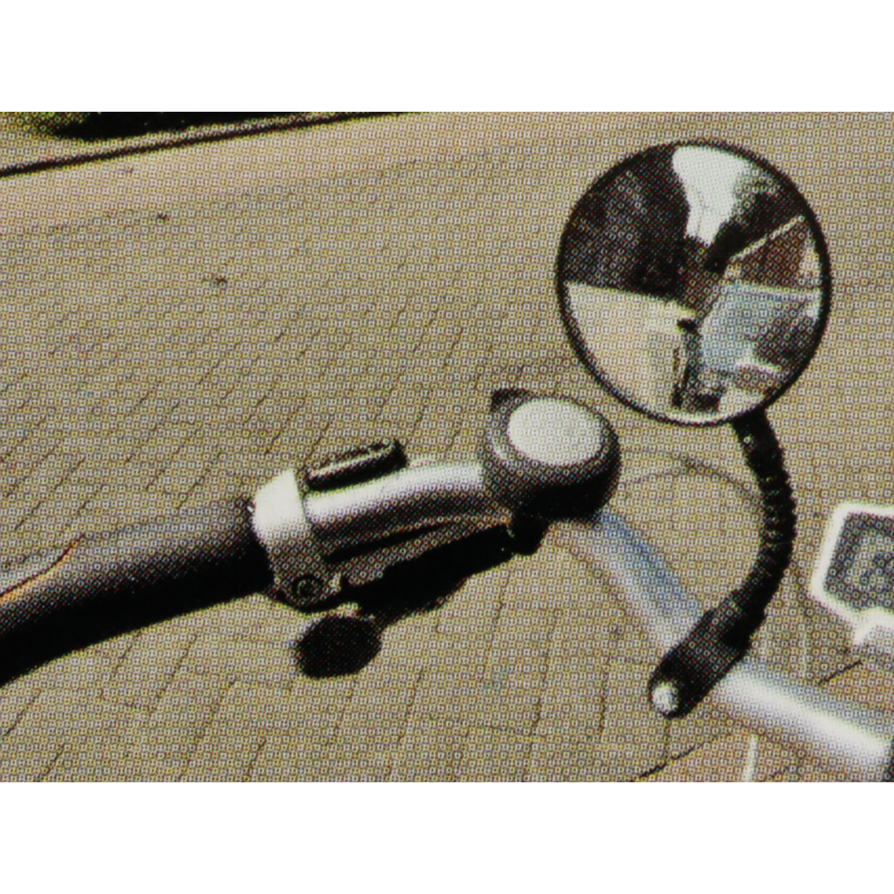 Fahrradlenker mit rundem Spiegel und Klingel auf gemustertem Untergrund.
